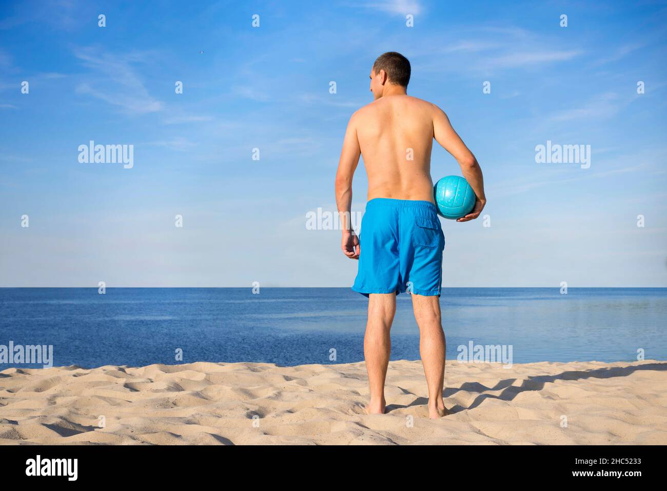 Jeune homme avec un volley sur la plage.Vue de l'arrière.Concept de vacances. Banque D'Images