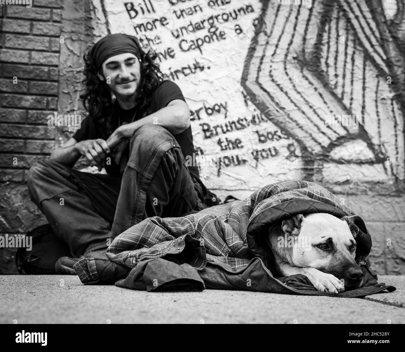 Photo en échelle de gris d'un homme sans abri et de son chien dans une rue de Moose Jaw, Canada Banque D'Images Photo en échelle de gris d'un homme sans abri et de son chien dans une rue de Moose Jaw, Canada Banque D'Images