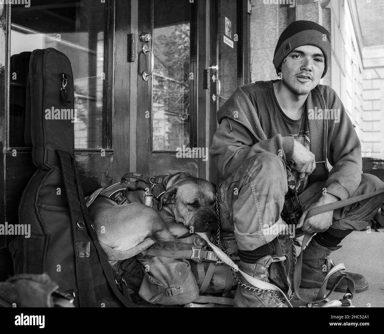 Photo en échelle de gris d'un homme sans abri et de son chien dans une rue de Moose Jaw, Canada Banque D'Images Photo en échelle de gris d'un homme sans abri et de son chien dans une rue de Moose Jaw, Canada Banque D'Images
