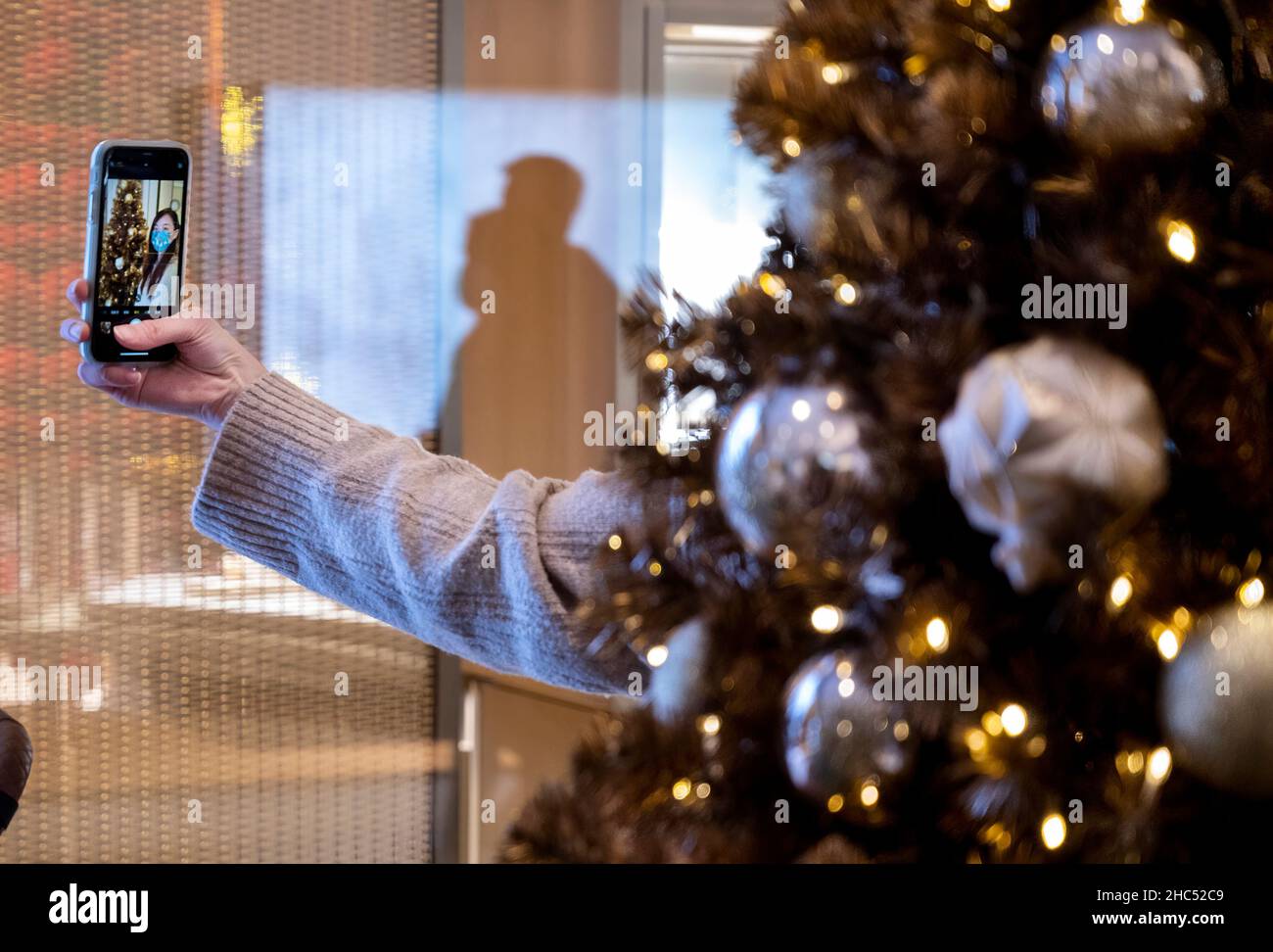 Hong Kong, Chine.11th décembre 2021.Une femme prend un selfie debout à côté d'un arbre de Noël doré dans un centre commercial de Hong Kong.(Image de crédit : © Miguel Candela/SOPA Images via ZUMA Press Wire) Banque D'Images
