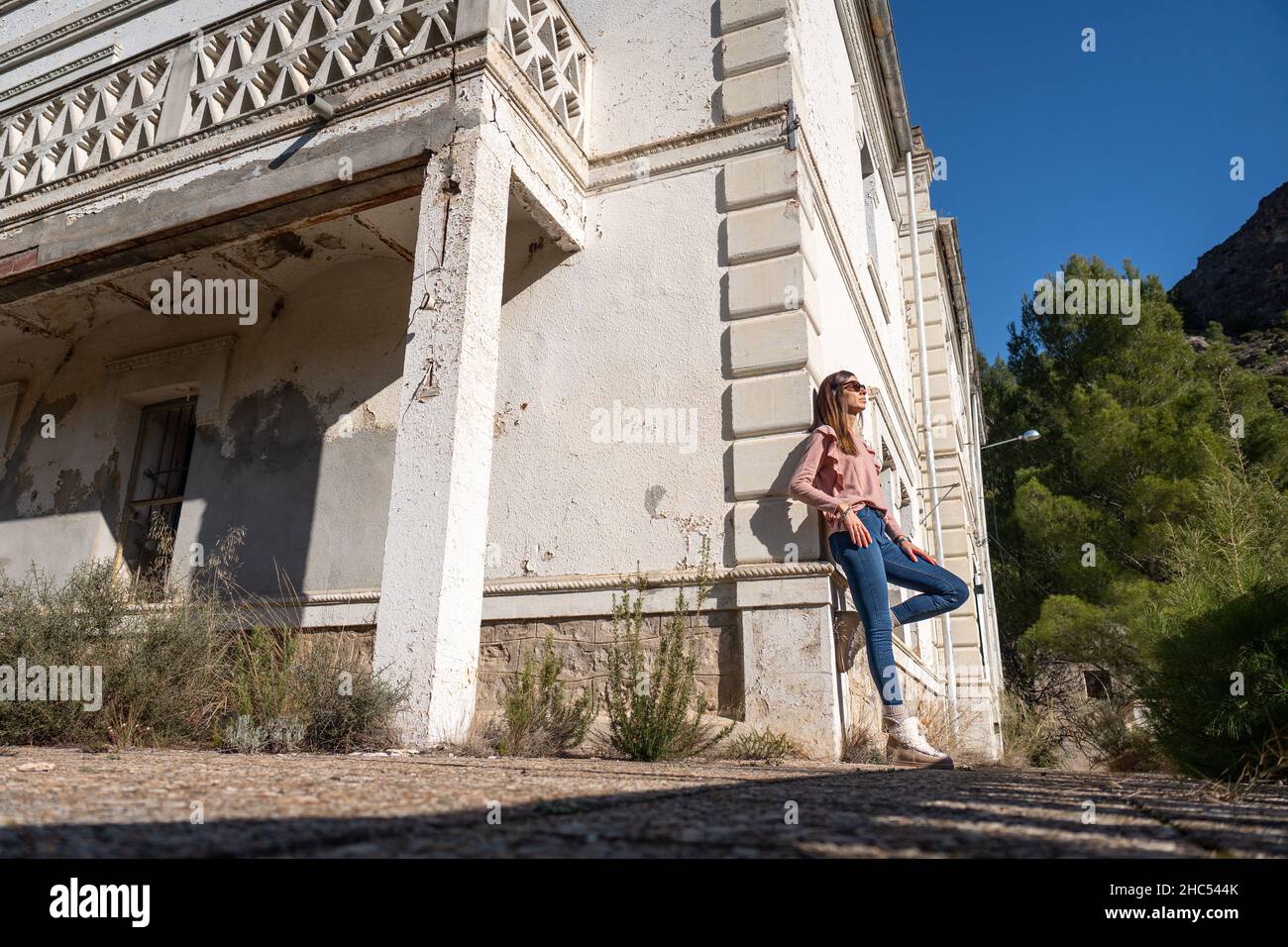 Jeune femme en Jean se penchait contre un mur blanc d'une maison en ruines Banque D'Images