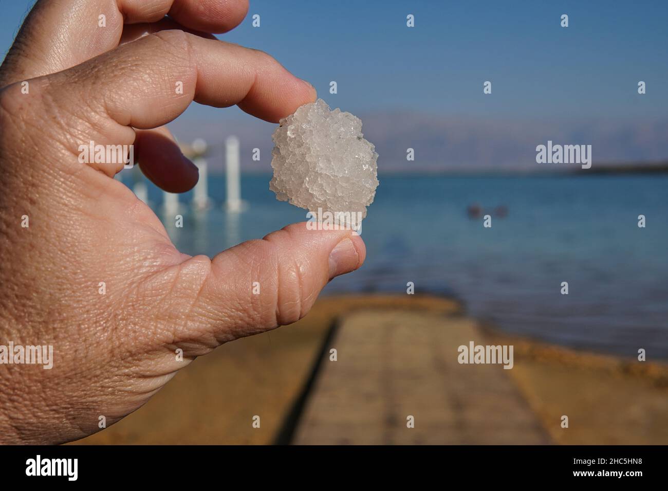 Vue sur les doigts qui retiennent le sel naturel et le cristal minéral de la mer morte Banque D'Images