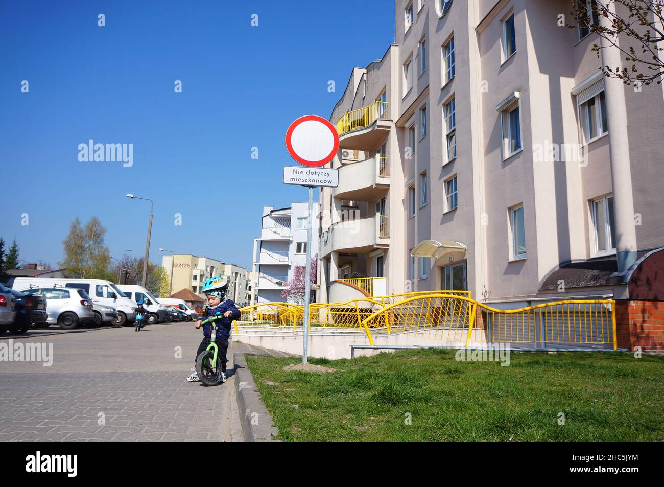 Garçon à vélo d'appartement dans la cour à côté d'un immeuble dans le quartier de Zegrze Banque D'Images