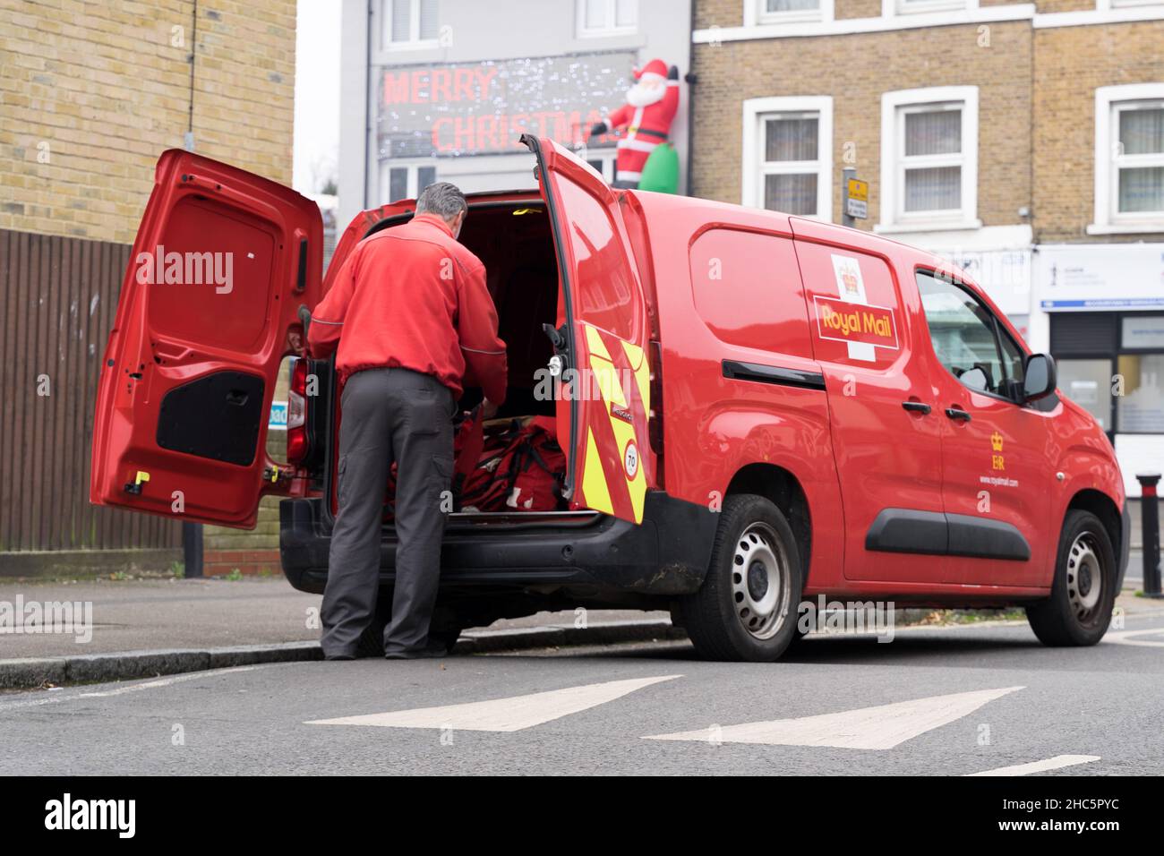Santa Postman ouvre les portes arrière pour livrer et distribuer des cadeaux de Noël à la communauté locale du sud de Londres Angleterre Royaume-Uni Banque D'Images