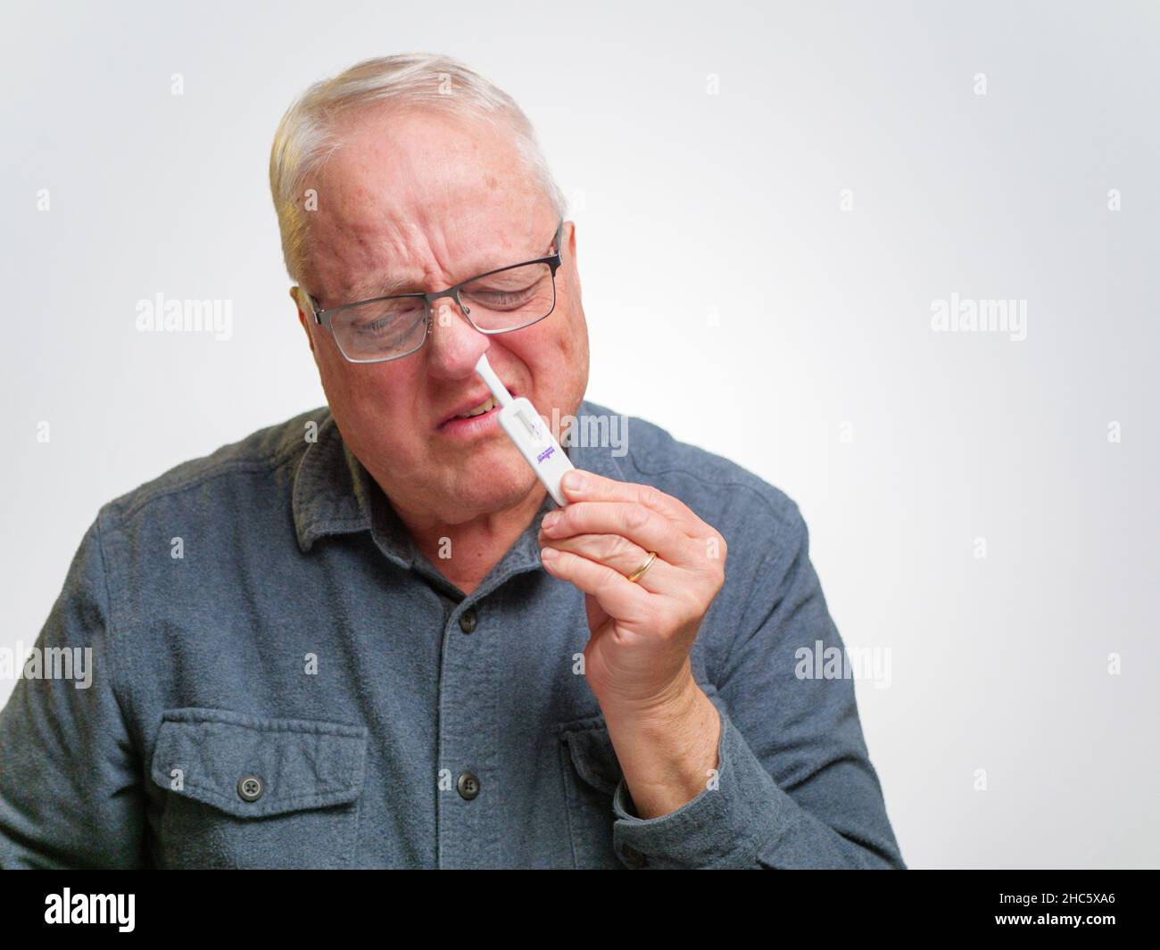 Homme à l'aide d'un kit de test d'antigène à domicile COVID-19. Banque D'Images