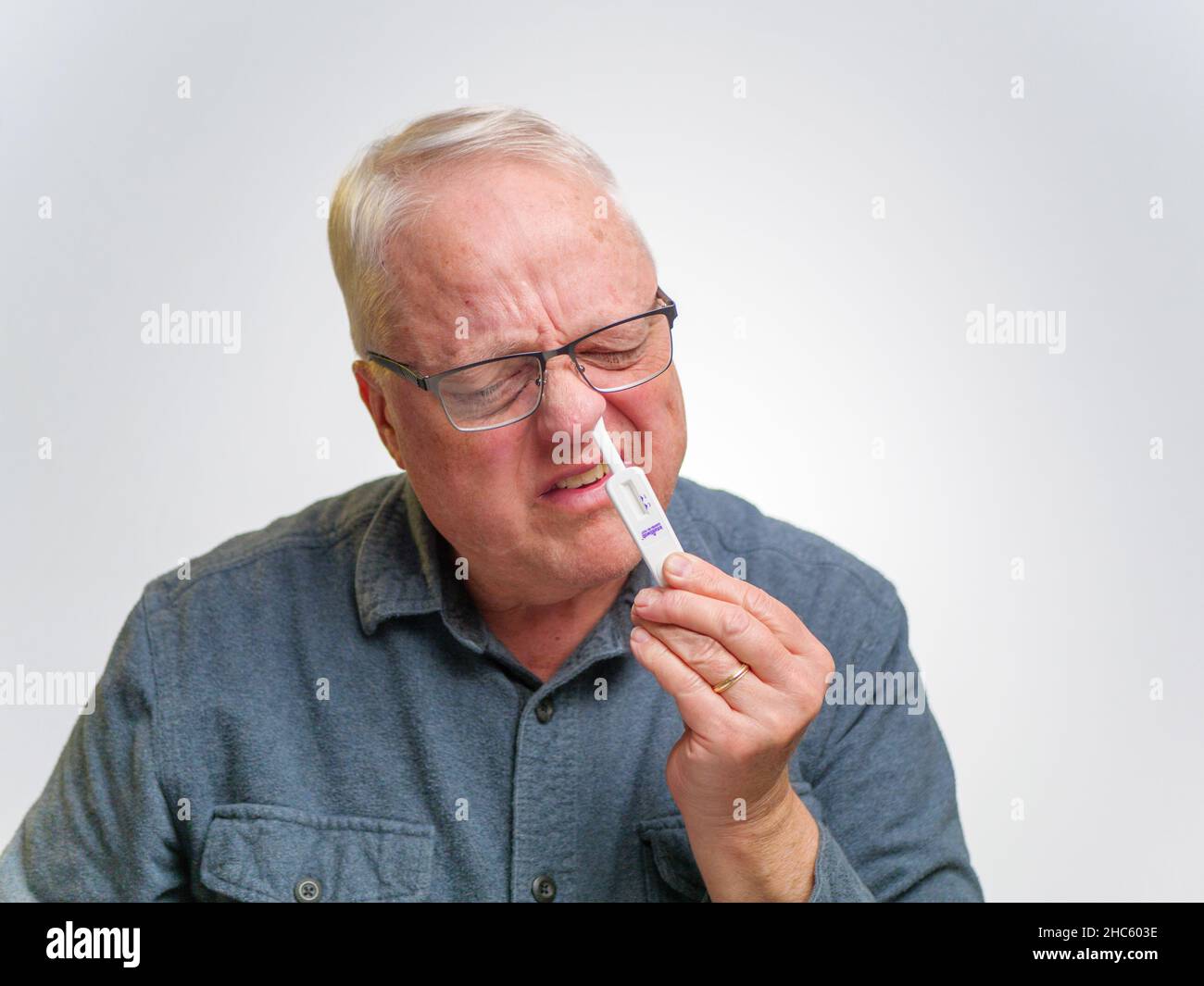 Homme à l'aide d'un kit de test d'antigène à domicile COVID-19. Banque D'Images