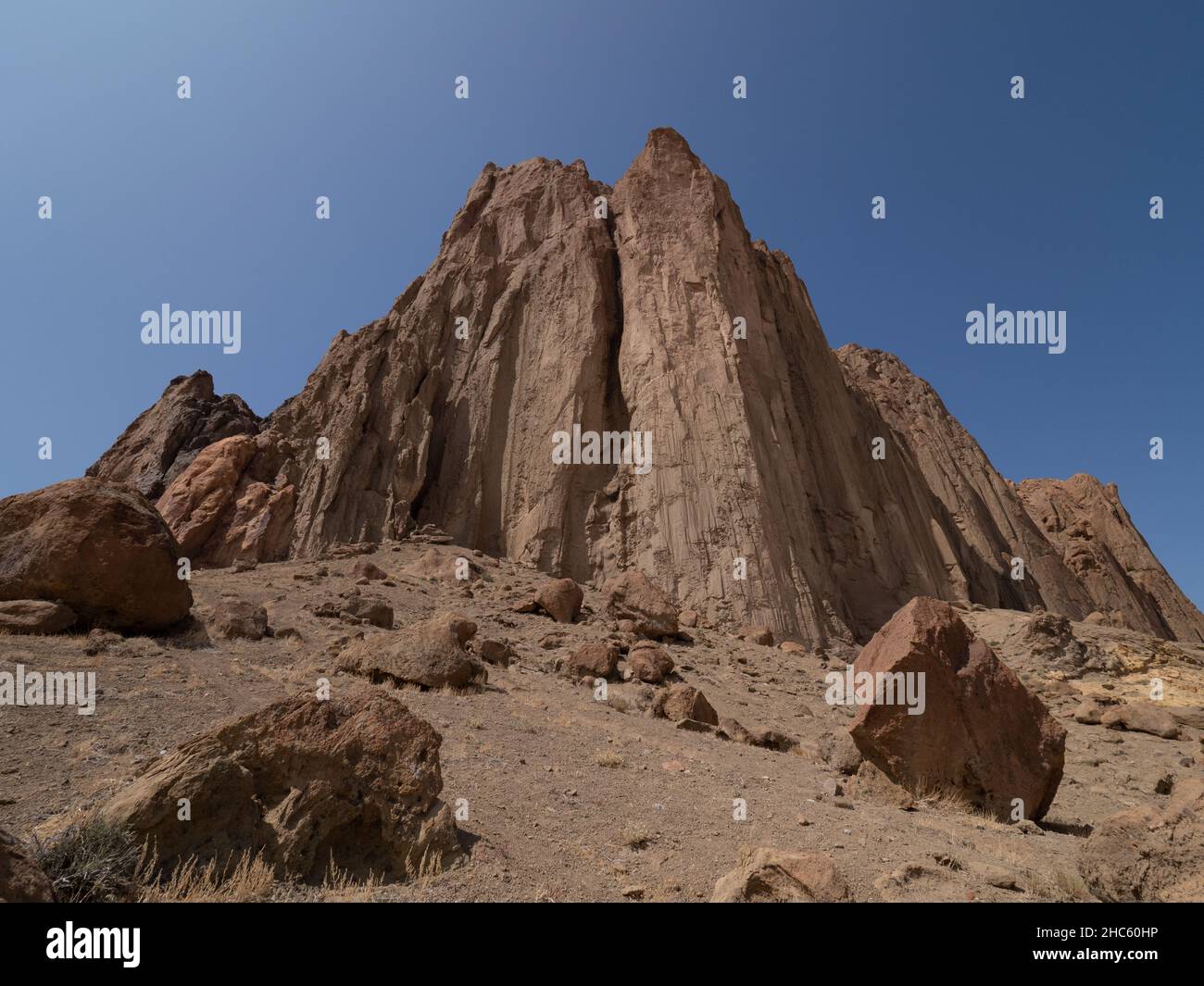Gros plan de la montagne Shiprock depuis la base avec de grands rochers éparpillés au premier plan et ciel bleu profond au-dessus. Banque D'Images