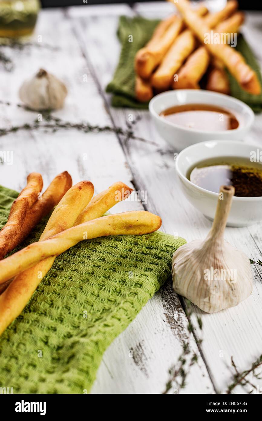 Gressins croustillants au graissini.Pain de blé italien traditionnel à l'ail, au fromage et aux graines de sésame.La cuisine est encore en vie sur fond rustique blanc Banque D'Images
