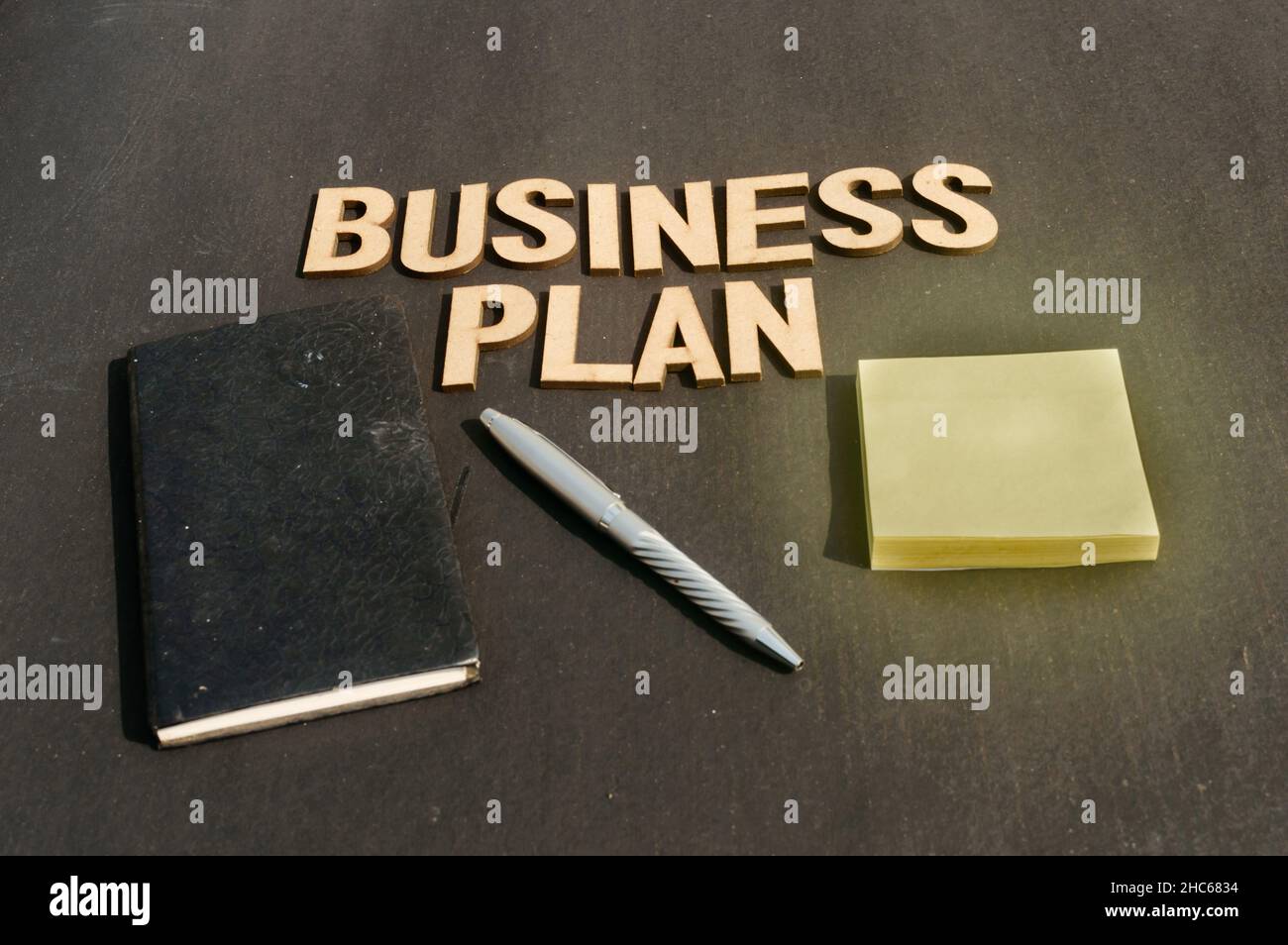 Main d'homme d'affaires plaçant un stylo et un carnet devant le plan d'affaires Word fait de blocs de bois de lettres Alphabet.Vue grand angle.Rétrogr. Vertical Banque D'Images