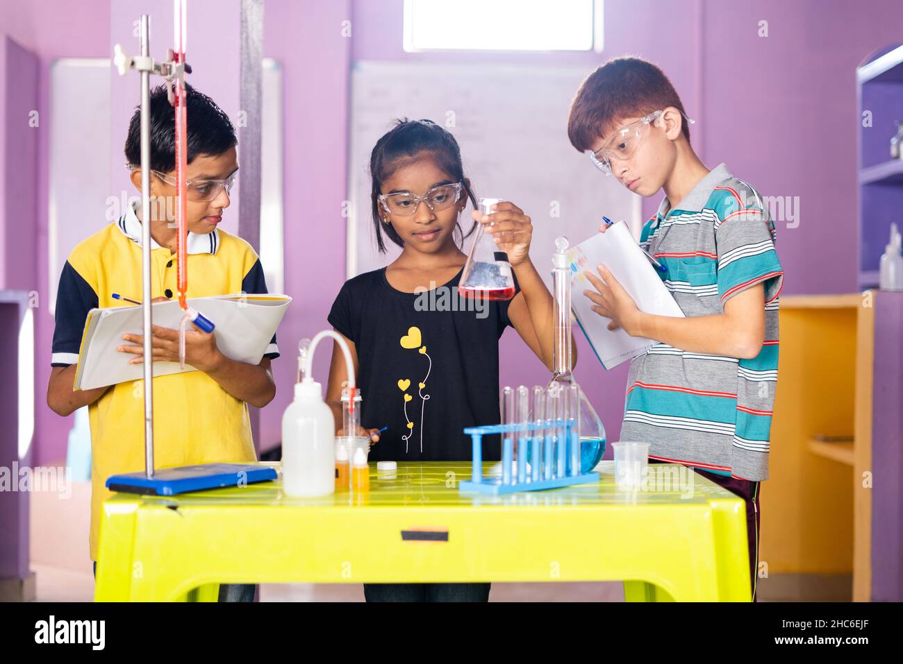 Concentrez-vous sur les filles, les enfants notant les produits chimiques de falsk en vérifiant au laboratoire de chimie - concept d'apprentissage de la réaction de réactif, l'éducation et Banque D'Images