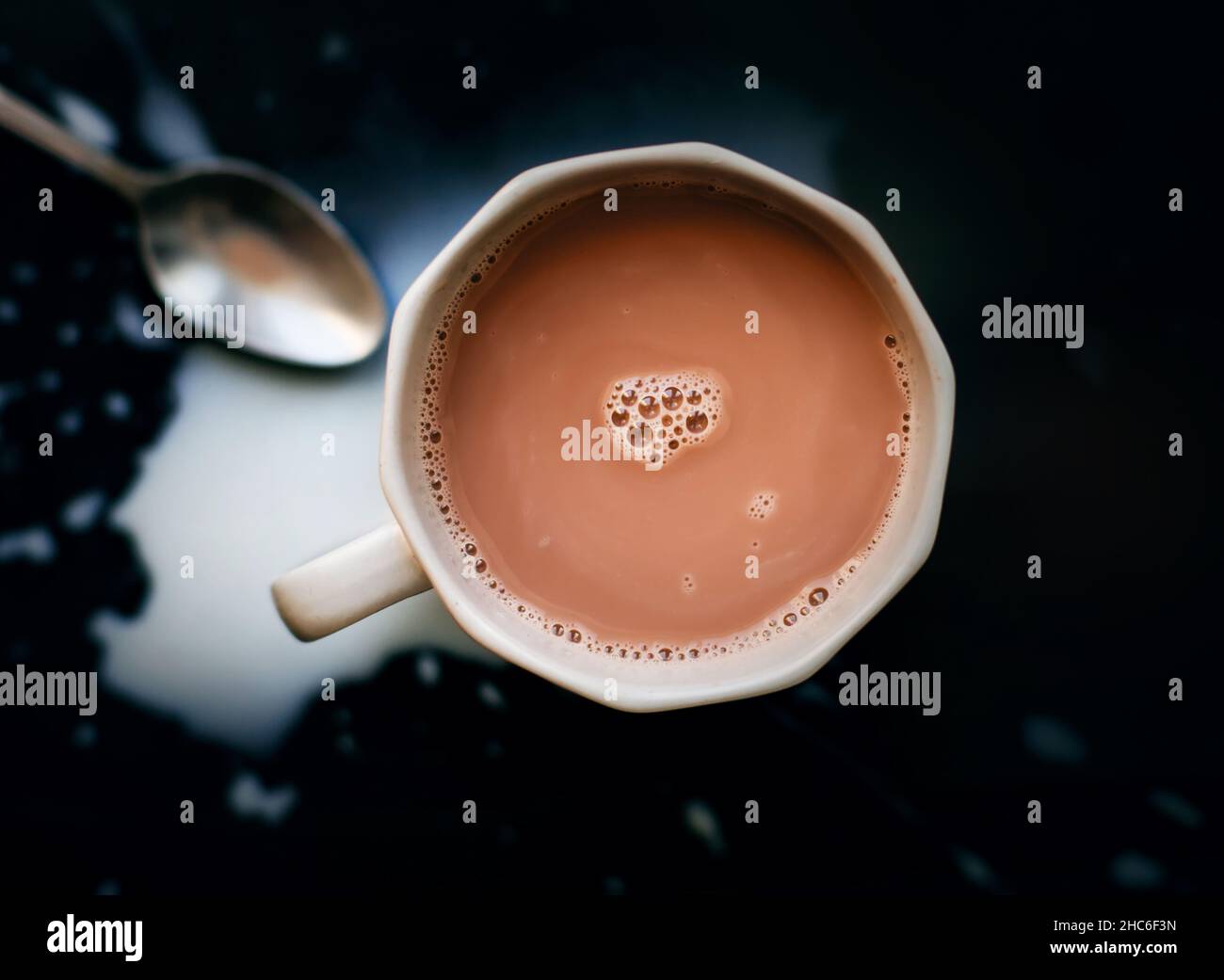 Vue de dessus d'une tasse grise de cacao naturel parfumé chaud, à côté de laquelle se trouve une cuillère à café d'argent et du lait renversé.Une boisson délicieuse pour le petit déjeuner. Banque D'Images Vue de dessus d'une tasse grise de cacao naturel parfumé chaud, à côté de laquelle se trouve une cuillère à café d'argent et du lait renversé.Une boisson délicieuse pour le petit déjeuner. Banque D'Images
