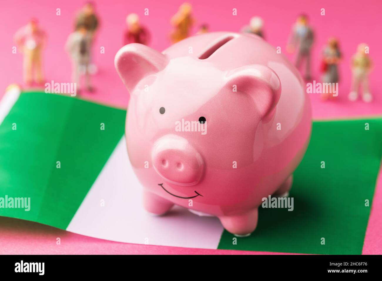 La banque de porc, le drapeau nigérian et les jouets en plastique sur fond coloré, le concept sur le thème du revenu de la population du Nigeria Banque D'Images