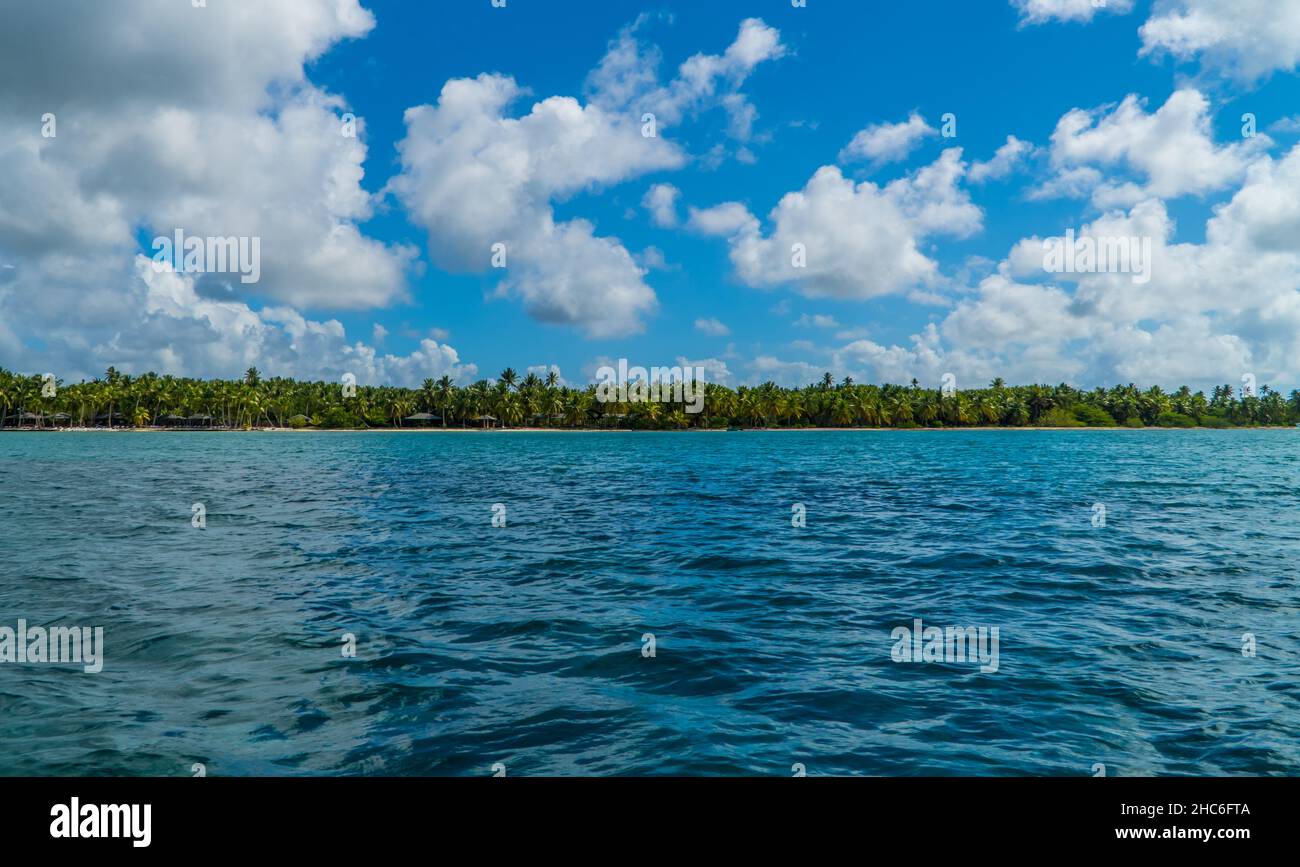 Vue sur l'eau bleue, les arbres verts à l'horizon avec un ciel nuageux à Isla Saona en République Dominicaine Banque D'Images