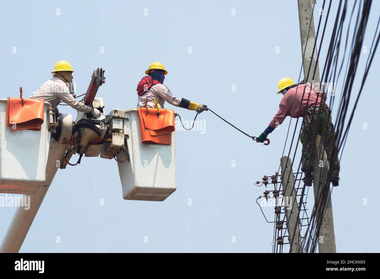 Les électriciens travaillent ensemble sur le téléphérique électrique et le poteau électrique.Maintenir le système de distribution haute et basse tension.Ils portent un casque W Banque D'Images