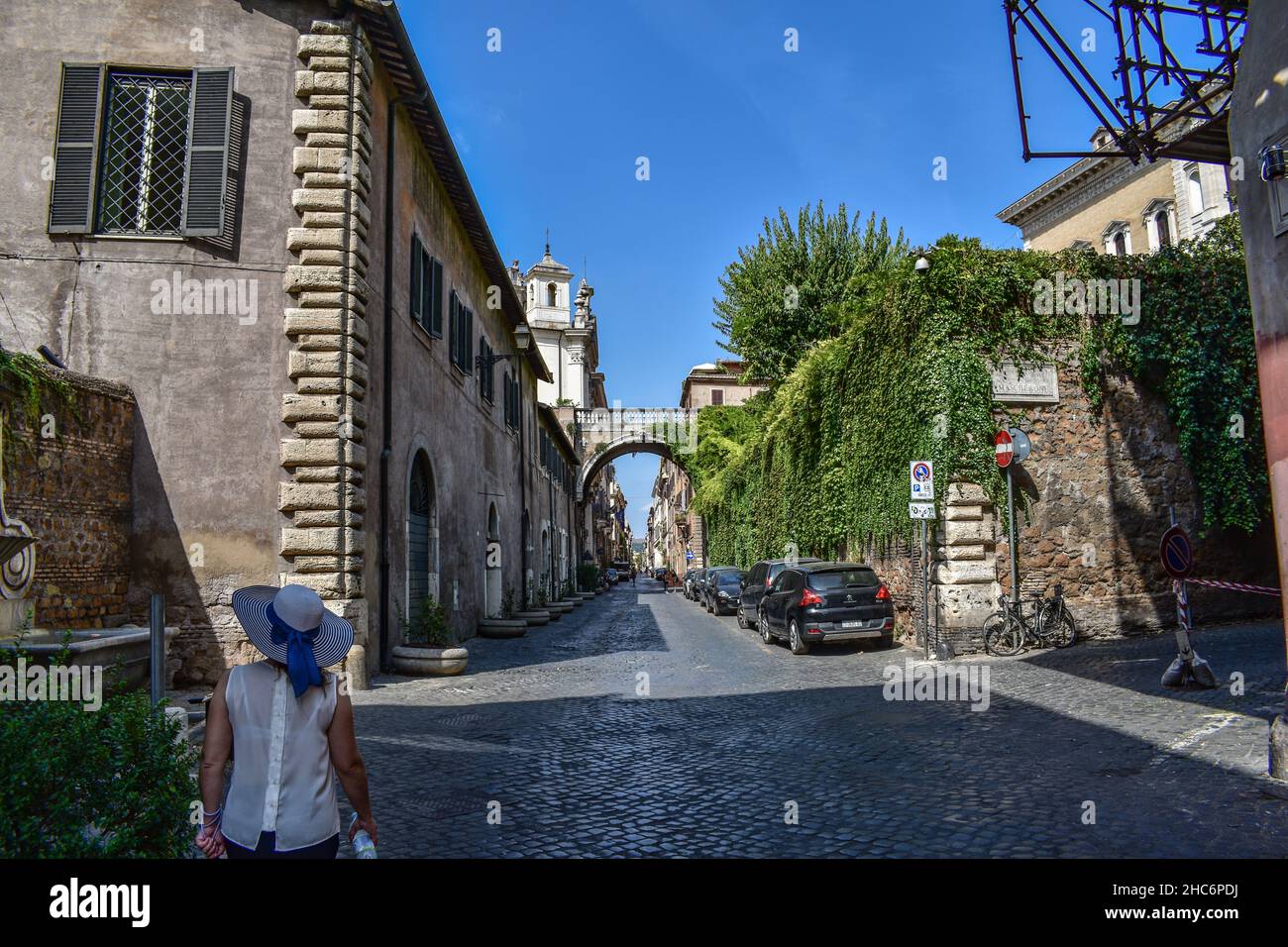 Vue arrière d'une femme portant un chapeau d'été dans une rue ensoleillée de Rome, Italie Banque D'Images