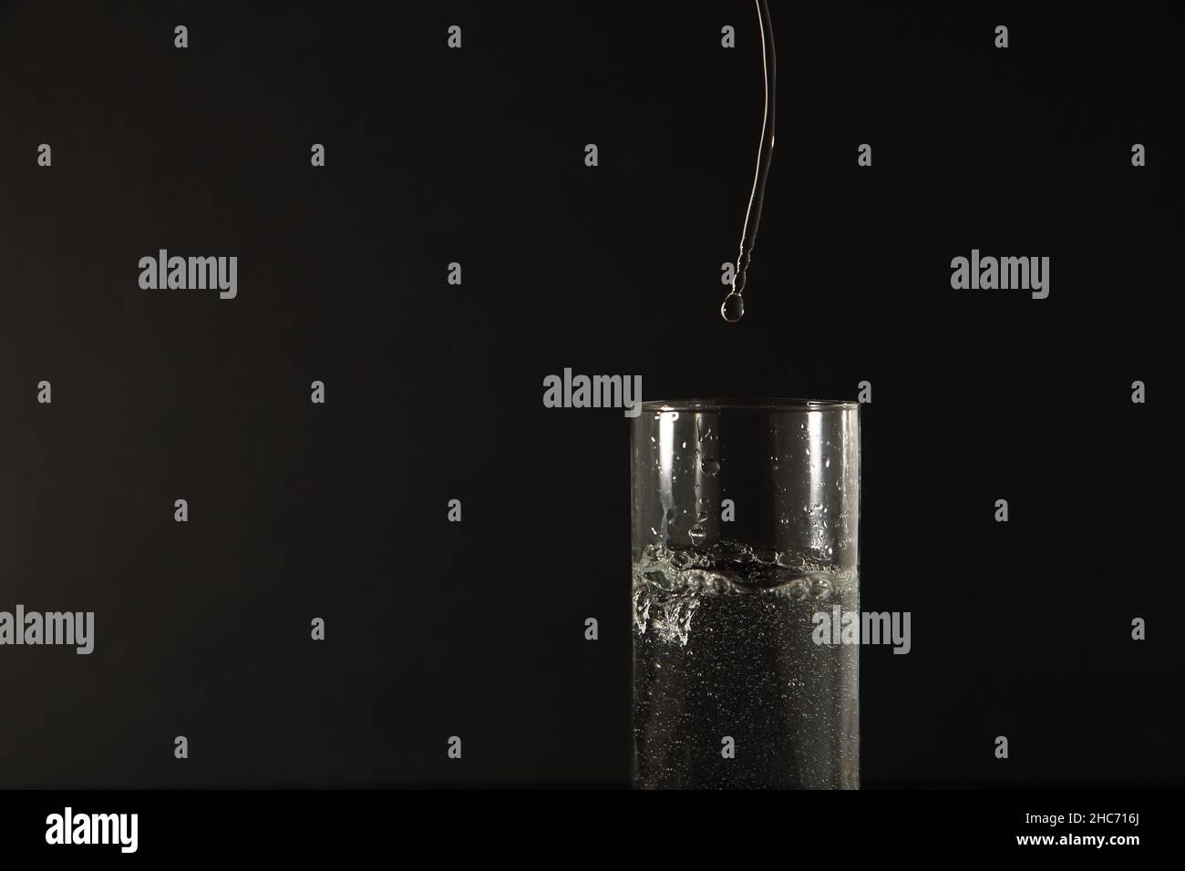 Glas de l'eau avec le courant d'eau pure mettre dans sur fond noir Banque D'Images