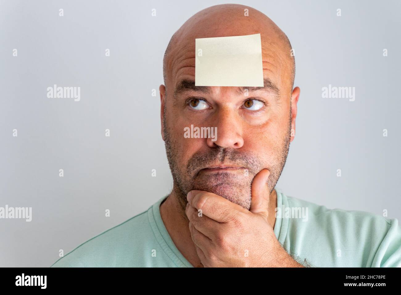 Gros plan sur le visage d'un homme caucasien à tête blanche et barbu avec un autocollant mémo. Banque D'Images