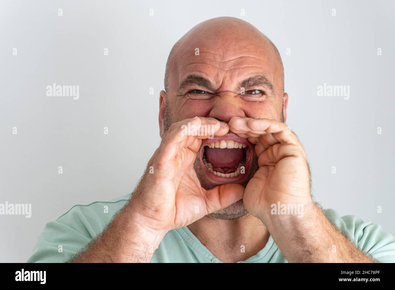 Gros plan d'un homme caucasien qui se fait le geste de crier avec les mains autour de la bouche ouverte Banque D'Images