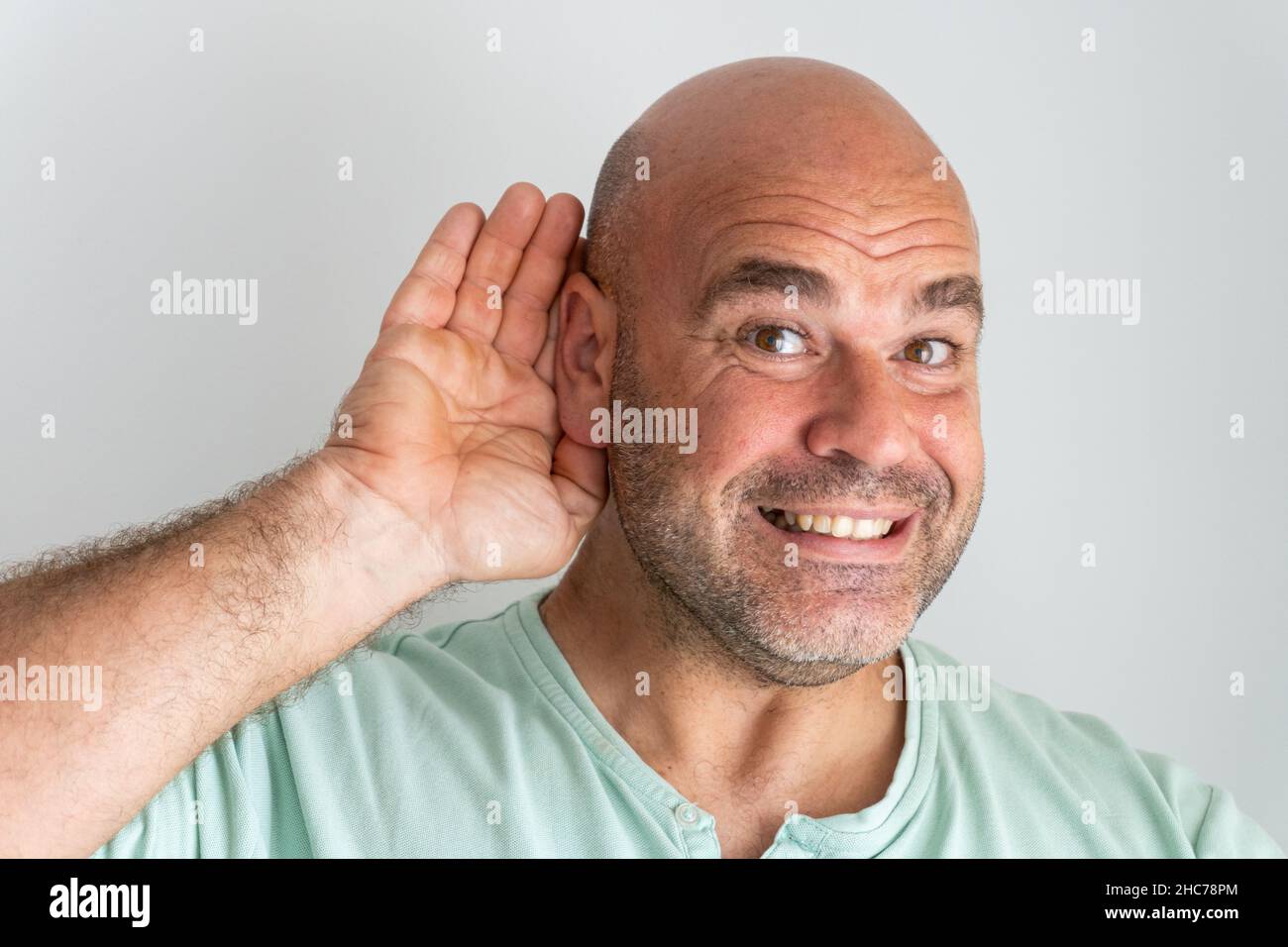 Gros plan sur le visage d'un homme caucasien à tête blanche et barbu qui gestait avec sa main derrière son oreille Banque D'Images