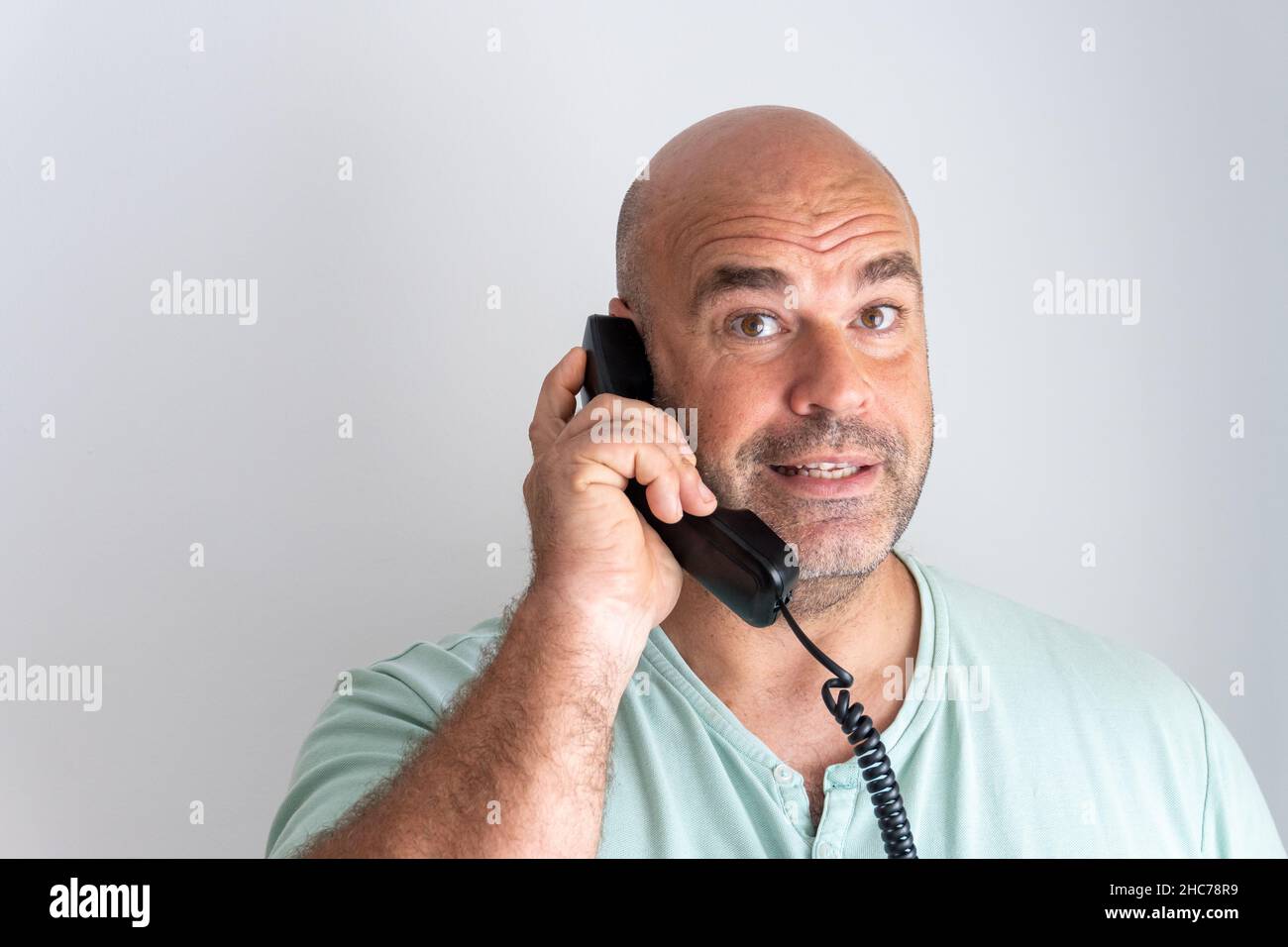 Gros plan d'un homme caucasien barbu et chauve qui parle sur le récepteur téléphonique Banque D'Images