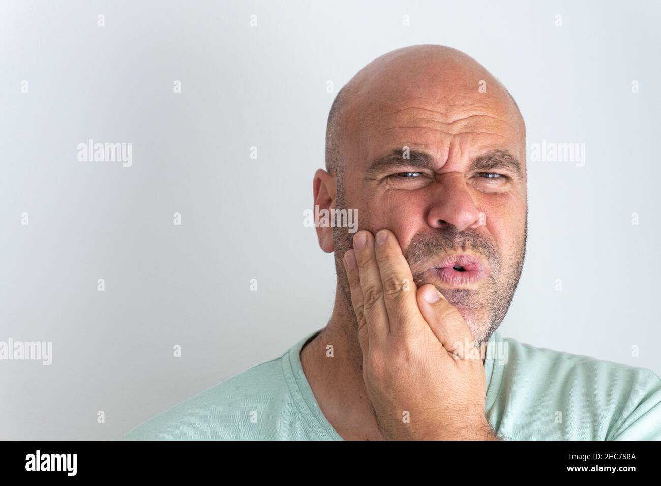 Gros plan d'un homme caucasien à barbe chauve qui gestuelle un mal de dents Banque D'Images