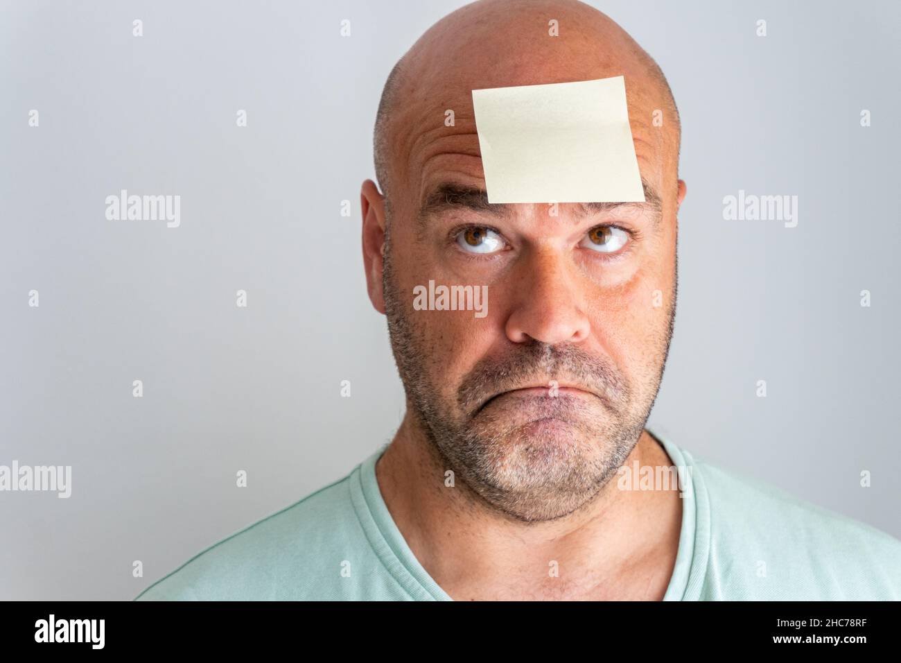 Gros plan sur le visage d'un homme caucasien à tête blanche et barbu avec un autocollant mémo Banque D'Images