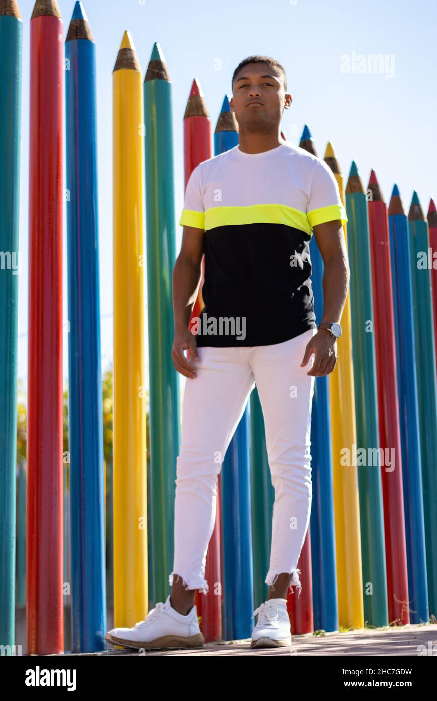 Portrait vertical d'un jeune latino sur la rue appuyé contre un mur Banque D'Images