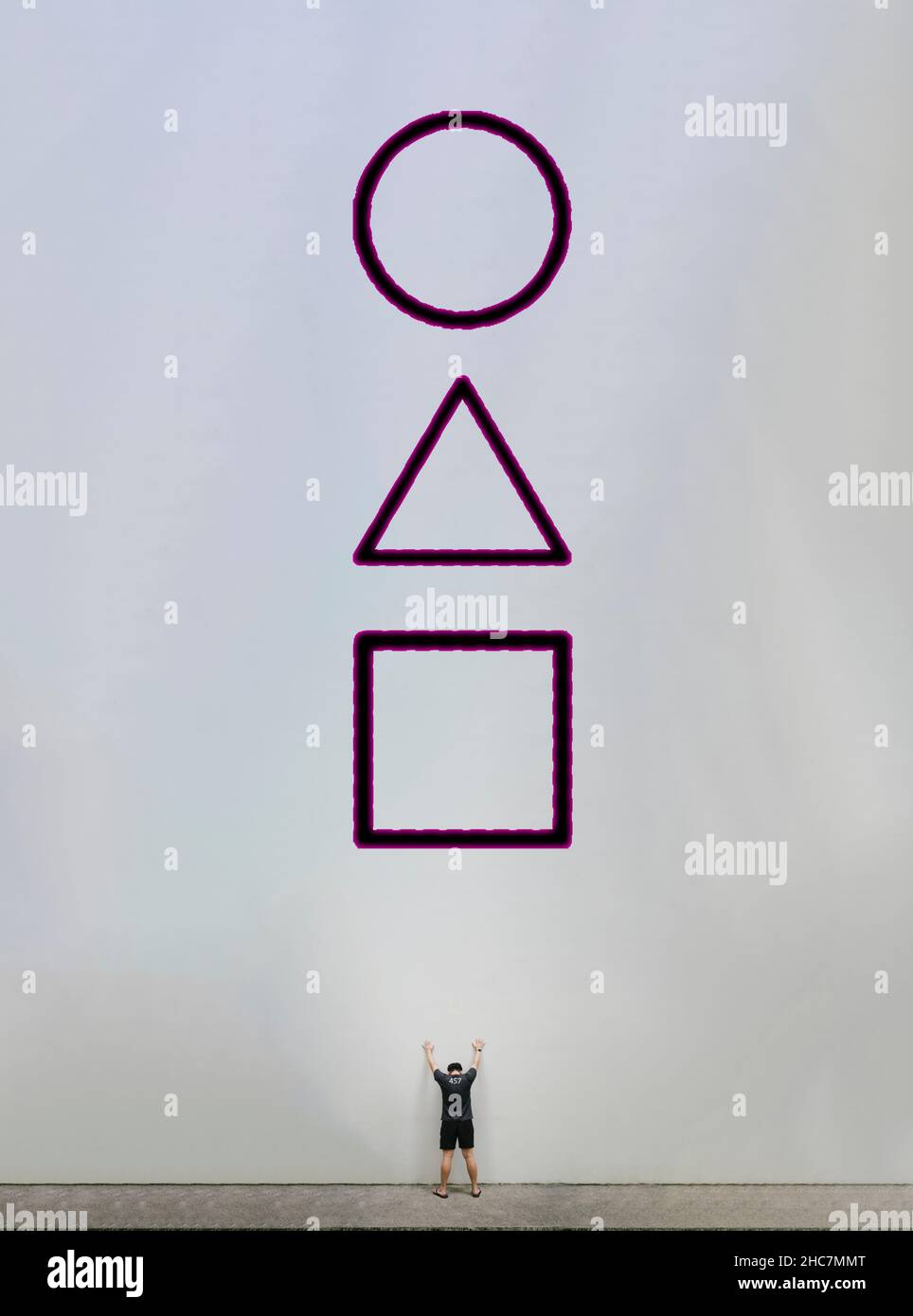 Joueur de jeu de squid debout face à un mur blanc logo géant Banque D'Images