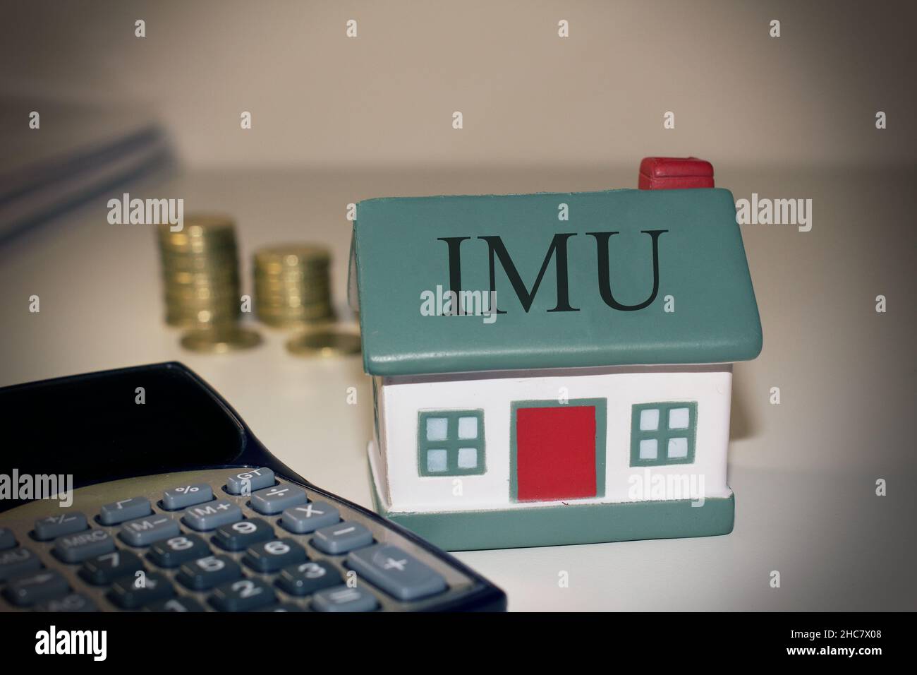 Maison avec un calcul et des pièces en euros avec le texte 'IMU' concept de la taxe italienne Banque D'Images