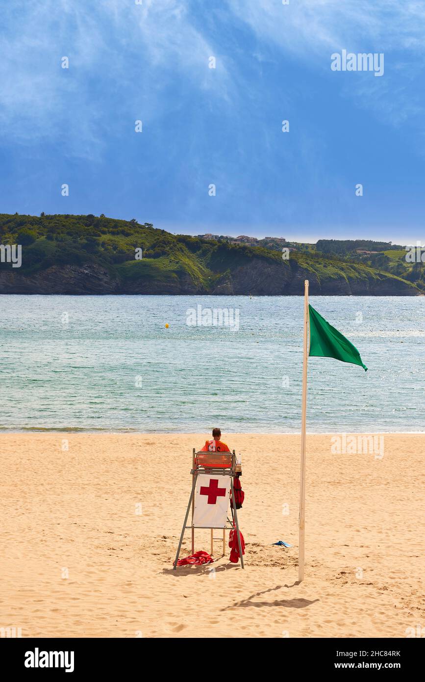 Sauveteur de croix rouge qui garde la plage avec un drapeau vert qui agite Banque D'Images