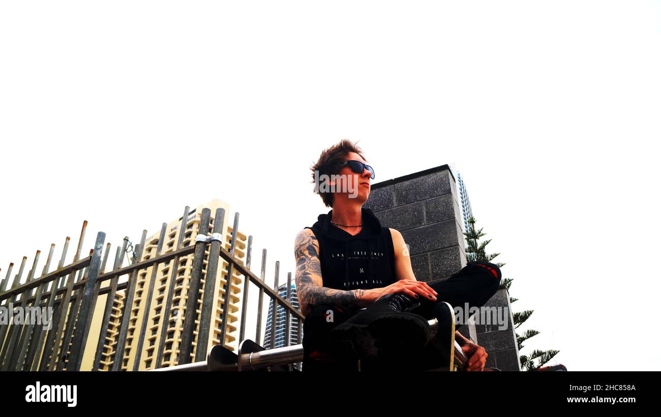 Prise de vue en angle d'un jeune homme adulte tatoué qui regarde à distance et envisage l'avenir Banque D'Images