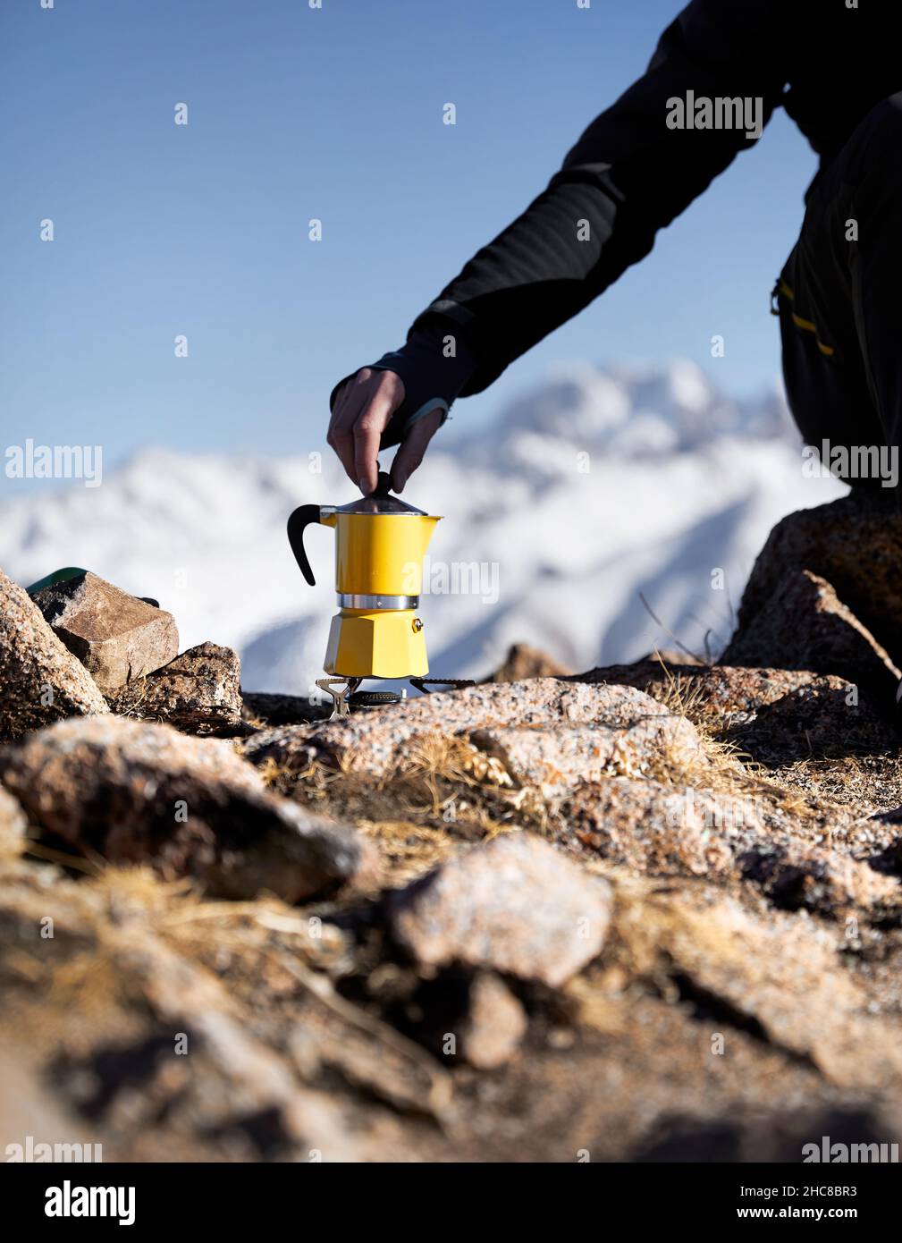 Homme randonneur qui fait du café à partir de Moka jaune pot de mocha en plein air dans les montagnes d'hiver de neige.Vieux style café pot vintage camping extérieur Banque D'Images