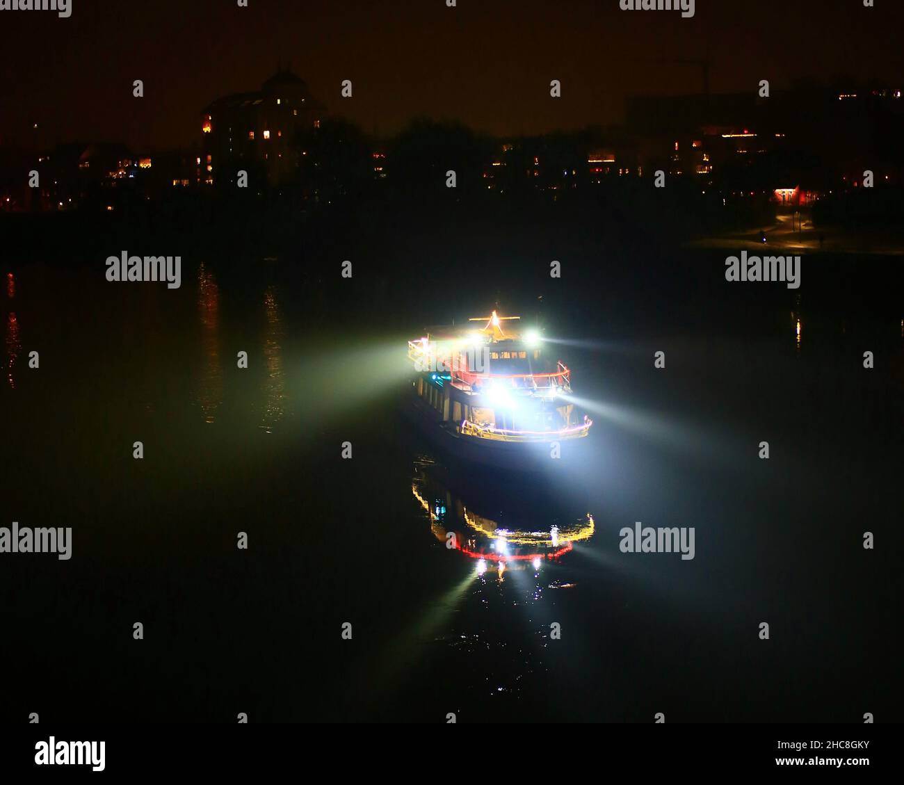 Petit bateau sur une rivière avec des lumières de recherche et d'illumination dans la nuit. Banque D'Images