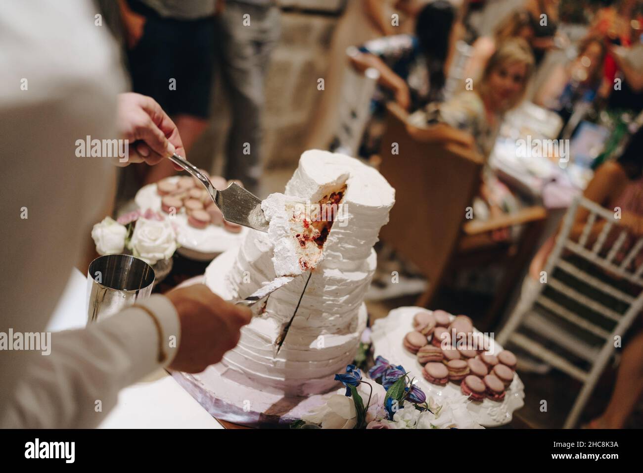 Les mains de l'homme tiennent un morceau de gâteau de mariage sur un couteau  et une spatule Photo Stock - Alamy