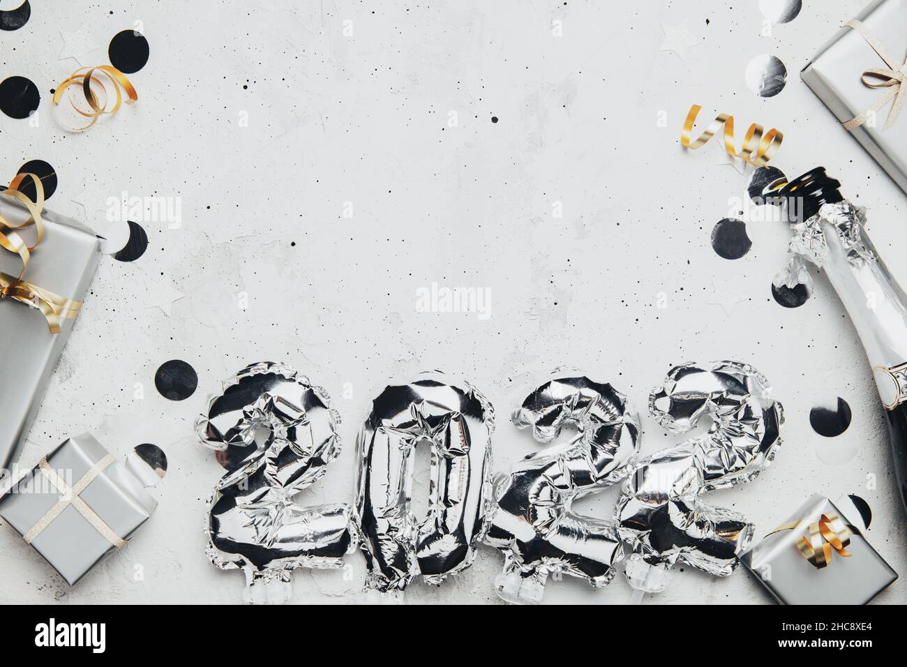 Nouvel an 2022 fond gris plat.Vue de dessus sur 2022 ballons argent numéros métalliques avec confetti, boîtes-cadeaux grises.Concept d'invitation ou de carte de vœux.Ambiance festive.Bouteille de champagne Banque D'Images