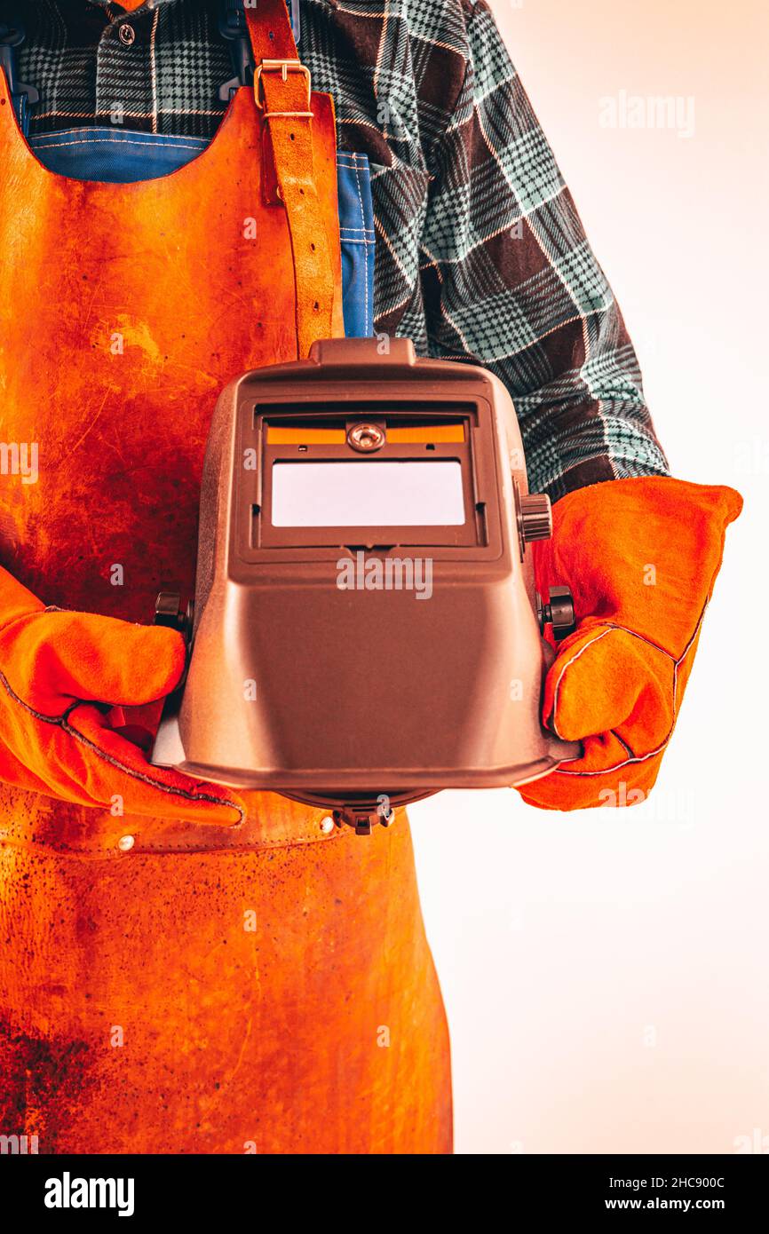 Travailleur de l'industrie lourde en costume de protection, gants, portant un masque de protection sous son bras, gros plan, photo verticale, couleurs vives Banque D'Images