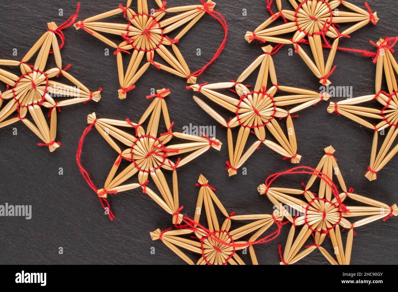 Plusieurs jouets de Noël en paille en forme d'étoile sur une pierre d'ardoise, vue rapprochée, vue de dessus. Banque D'Images
