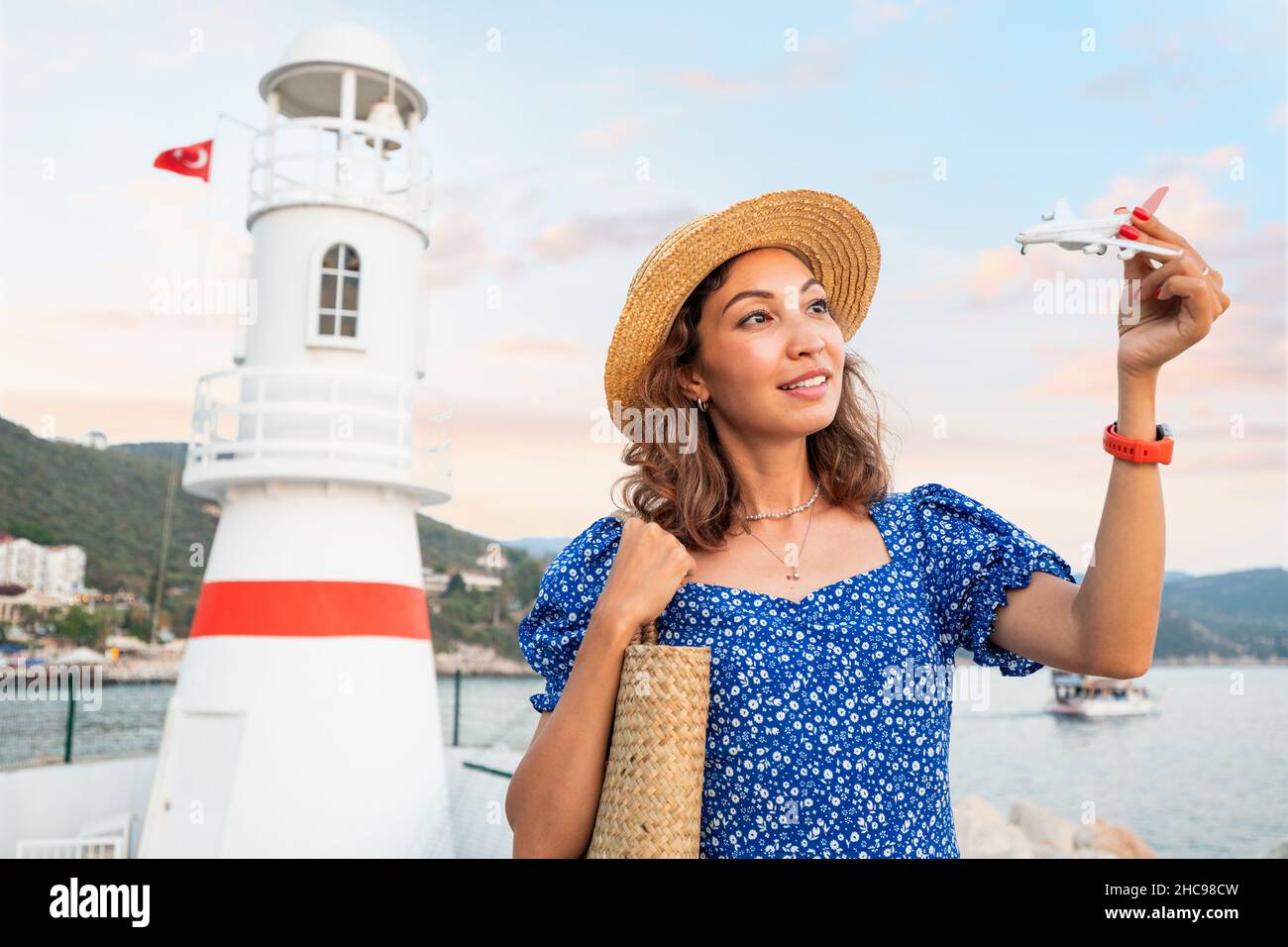 Voyageur femme avec petit avion jouet à la main sur le fond d'un phare dans la ville de Kas en Turquie.Le concept d'une compagnie aérienne et l'ouverture o Banque D'Images