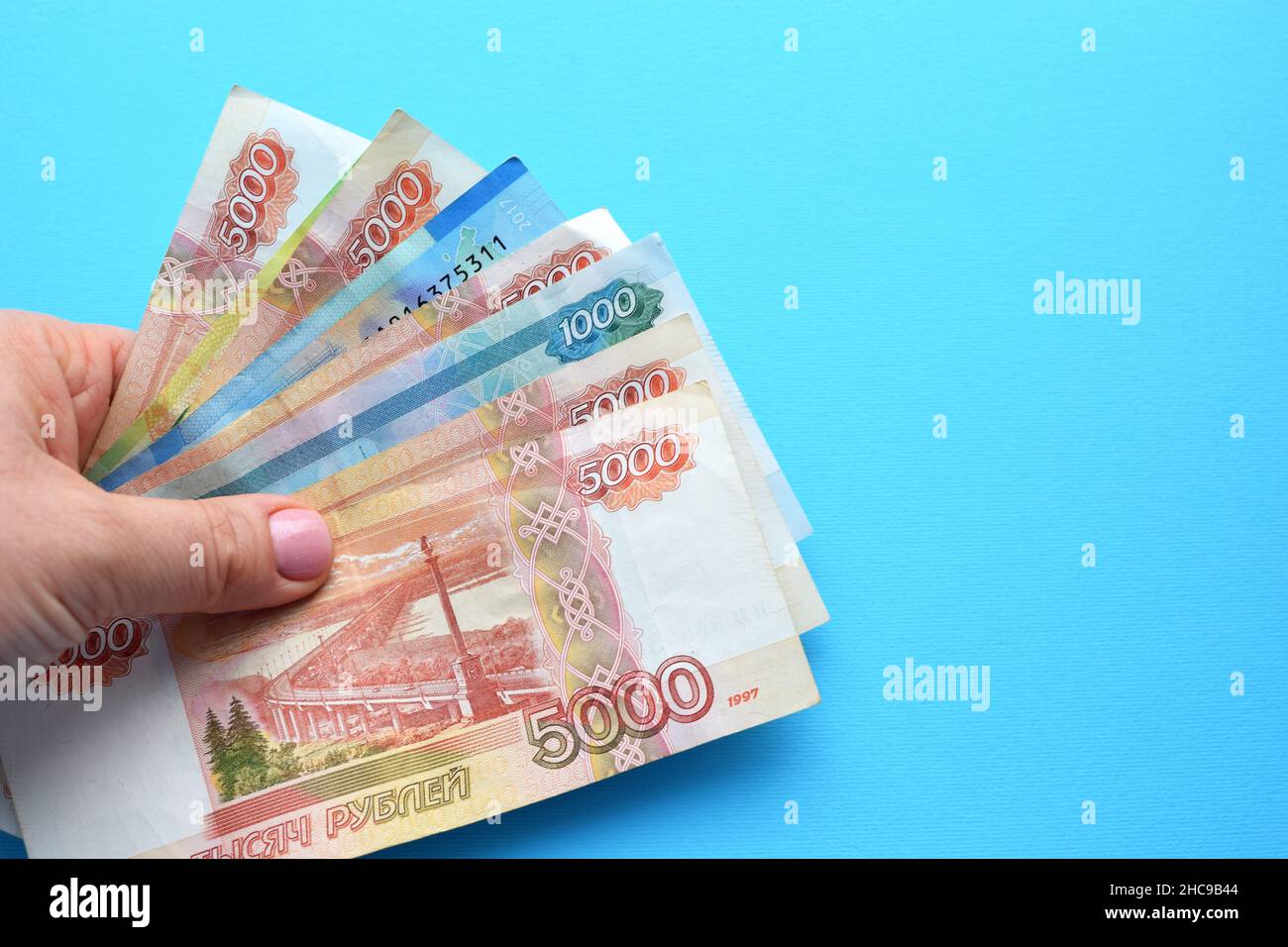 Billets de rouble russes dans une main femelle sur fond bleu. Banque D'Images