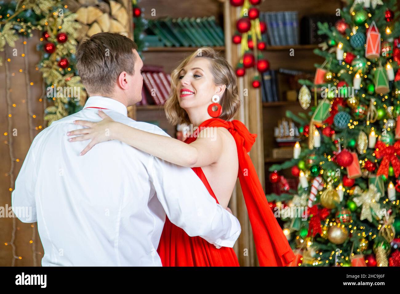 beau couple dansant dans la salle de séjour décorée par arbre de noël célébrant la fête du nouvel an Banque D'Images