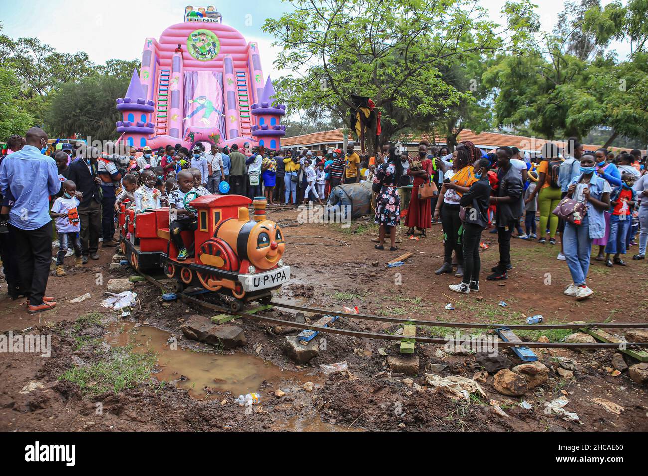 Nairobi, Kenya.25th décembre 2021.Les enfants kenyans se mettent à prendre un train à jouets tandis que leurs parents regardent un carnaval le jour de Noël.Pendant de nombreuses années, les Kenyans vivant à Nairobi et ses environs passent le jour de Noël dans les parcs d'Uhuru et Central.Toutefois, ce n'est pas le cas cette année, car les deux parcs restent fermés pour rénovations.Cela ne les a pas empêcher de profiter de la journée dans de petits espaces disponibles.Crédit : SOPA Images Limited/Alamy Live News Banque D'Images