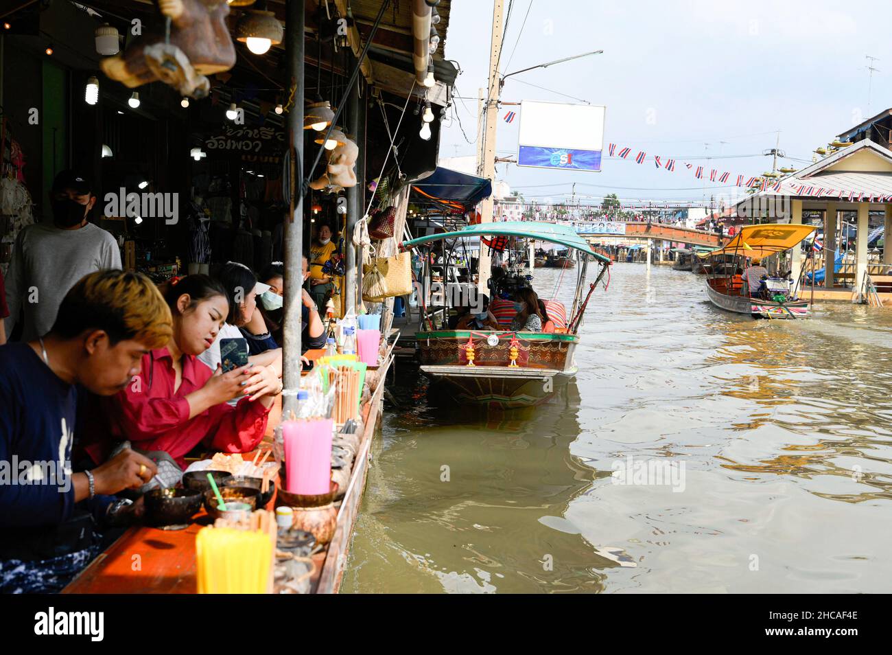 Amphawa, Thaïlande.26th décembre 2021.On voit les gens manger au marché flottant d'Amphawa, à environ 90km au sud-ouest de Bangkok, dans la province de Samut Songkhram, ouvert sur Fridayís, Saturday et Sundayís.Les bateaux motorisés à longue queue offrent aux touristes des promenades en bateau à travers une série de klongs (canaux), et une foule de voies d'eau avec des boutiques vendant une variété de bonbons thaïlandais, poissons séchés et herbes, de nombreux restaurants offrent également des plats de soupe de nouilles et des jus de fruits exotiques.Les communautés du marché flottant sont considérées comme un patrimoine culturel thaïlandais précieux.Crédit : SOPA Images Limited/Alamy Live News Banque D'Images