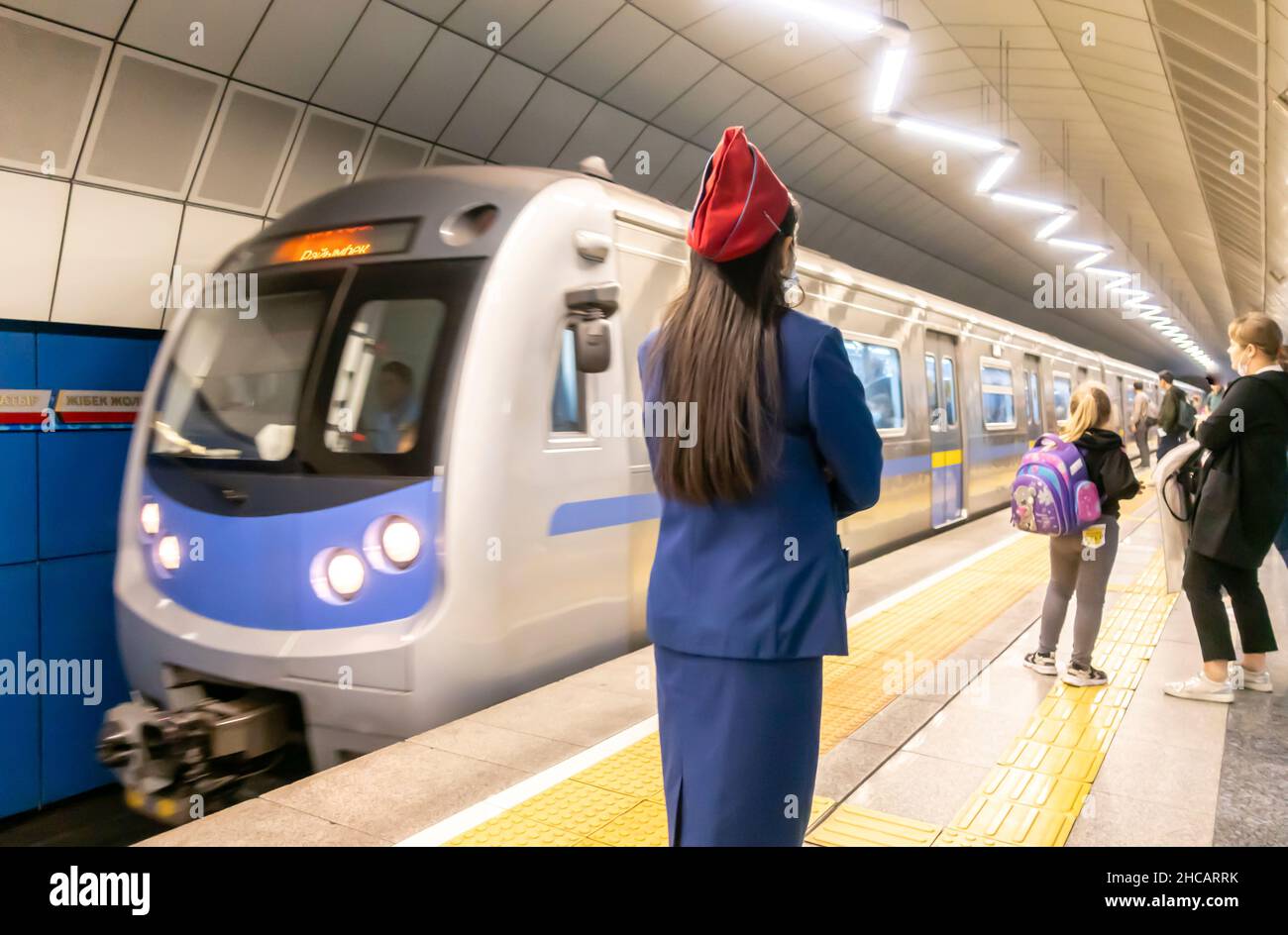 Le train arrive à la station de métro Baykonur à Almaty, Kazakhstan, Central, Asie.Employée de la métropole féminine contrôlant le trafic. Banque D'Images