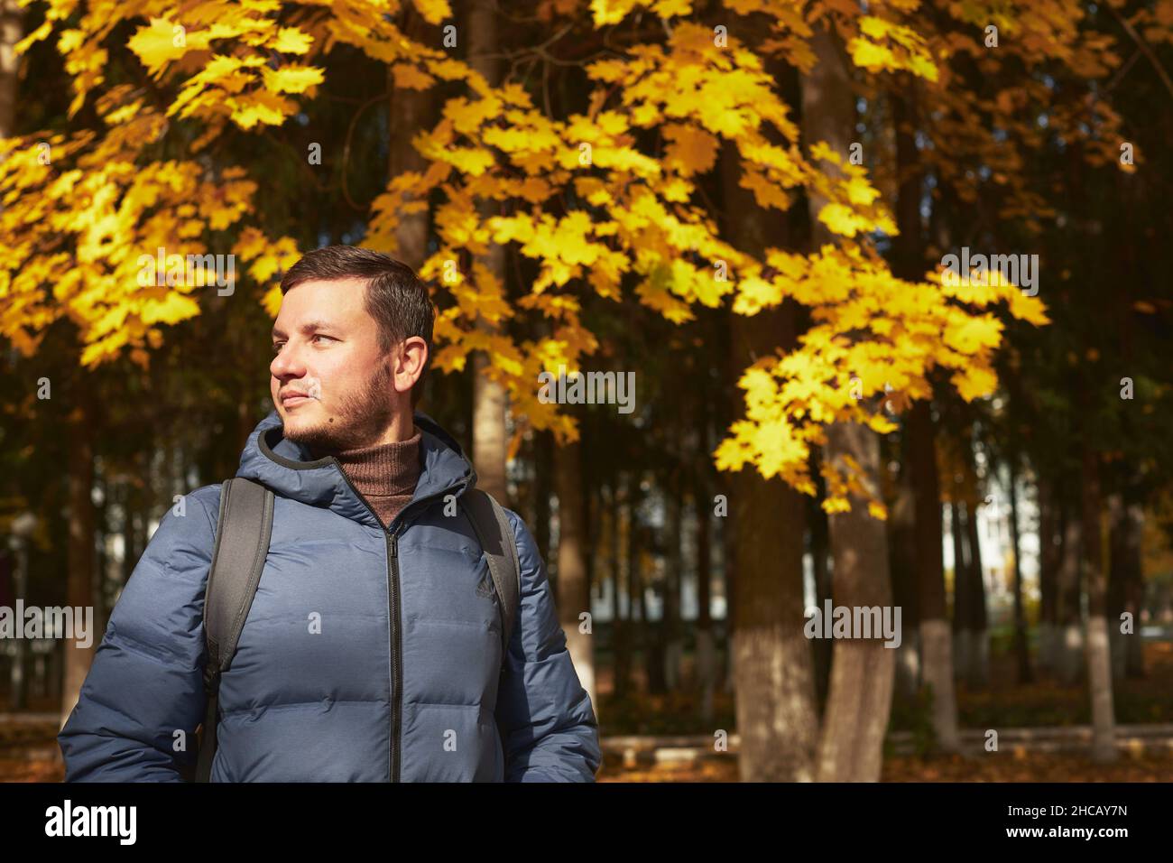 Portrait d'un beau homme dans la forêt d'automne dans une veste et une écharpe en duvet.Vue avant. Banque D'Images