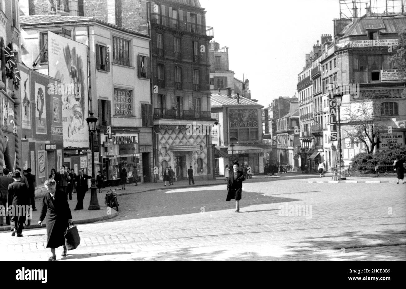 Place Pigalle, avec piétons et pas d'automobiles, avril 1945.La vue principale donne vers le sud-ouest sur une place presque vide en direction des Folies Pigalle et de la rue Jean-Baptiste Pigalle.L'image est pleine de signalisation et de publicités.Environ deux douzaines de Parisiens sont vus en train de faire des affaires ou de converser dans la rue. Banque D'Images