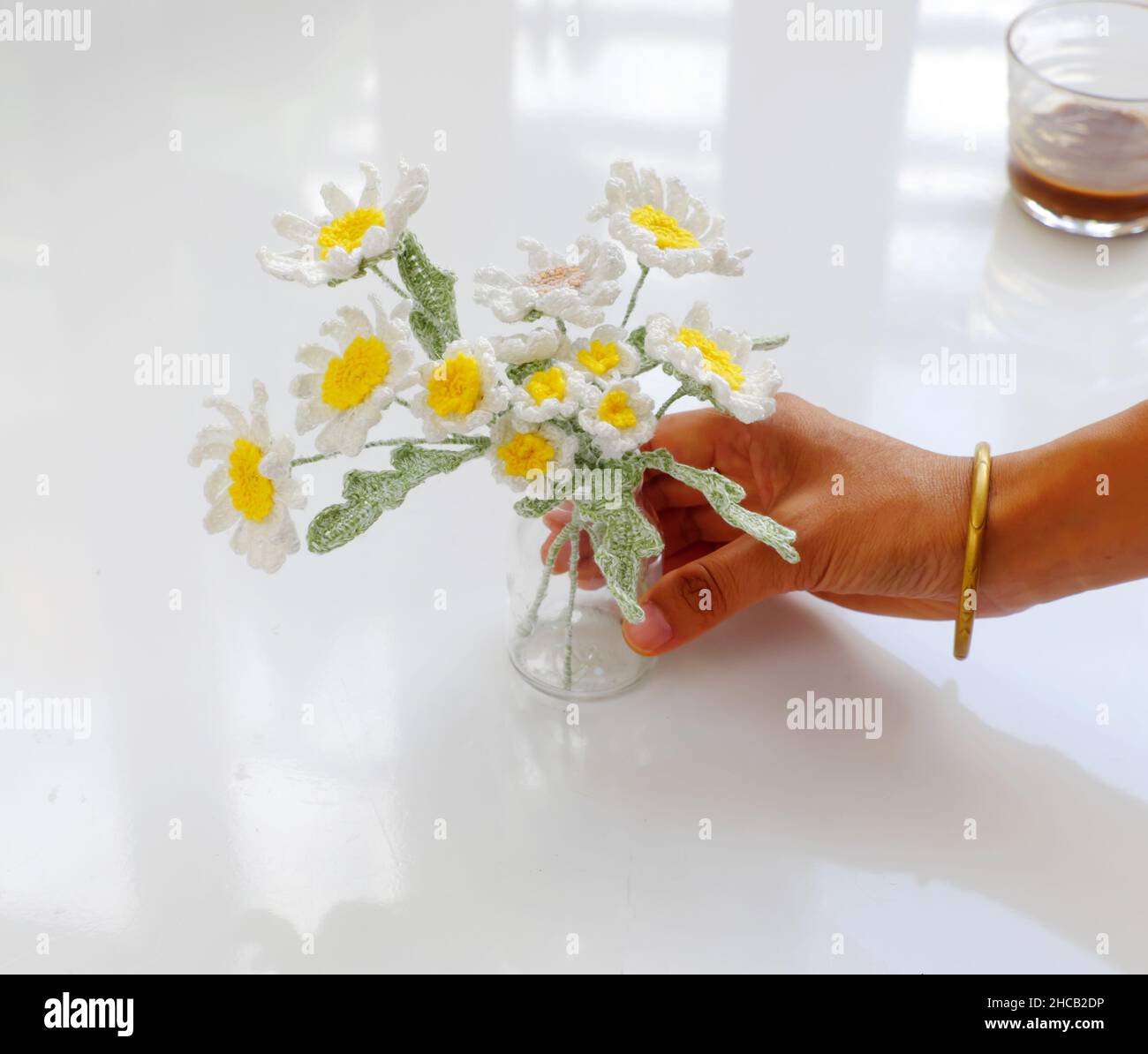 Femme tient main pot de fleur fait main pour la décoration de la maison, pâquerette blanche et crochet jaune pistil à partir de fils à des activités de loisirs sur fond blanc Banque D'Images