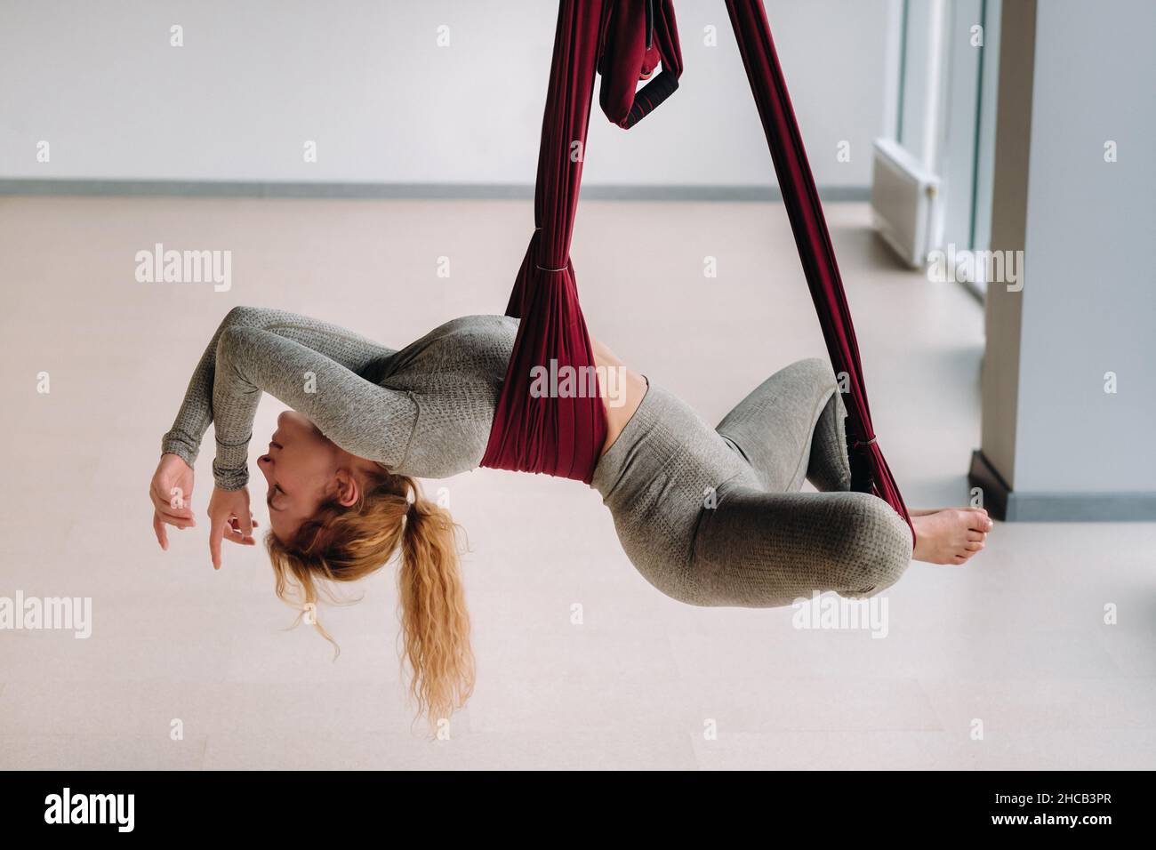 Une femme accrochée à un hamac suspendu fait du yoga dans la salle de gym  Photo Stock - Alamy