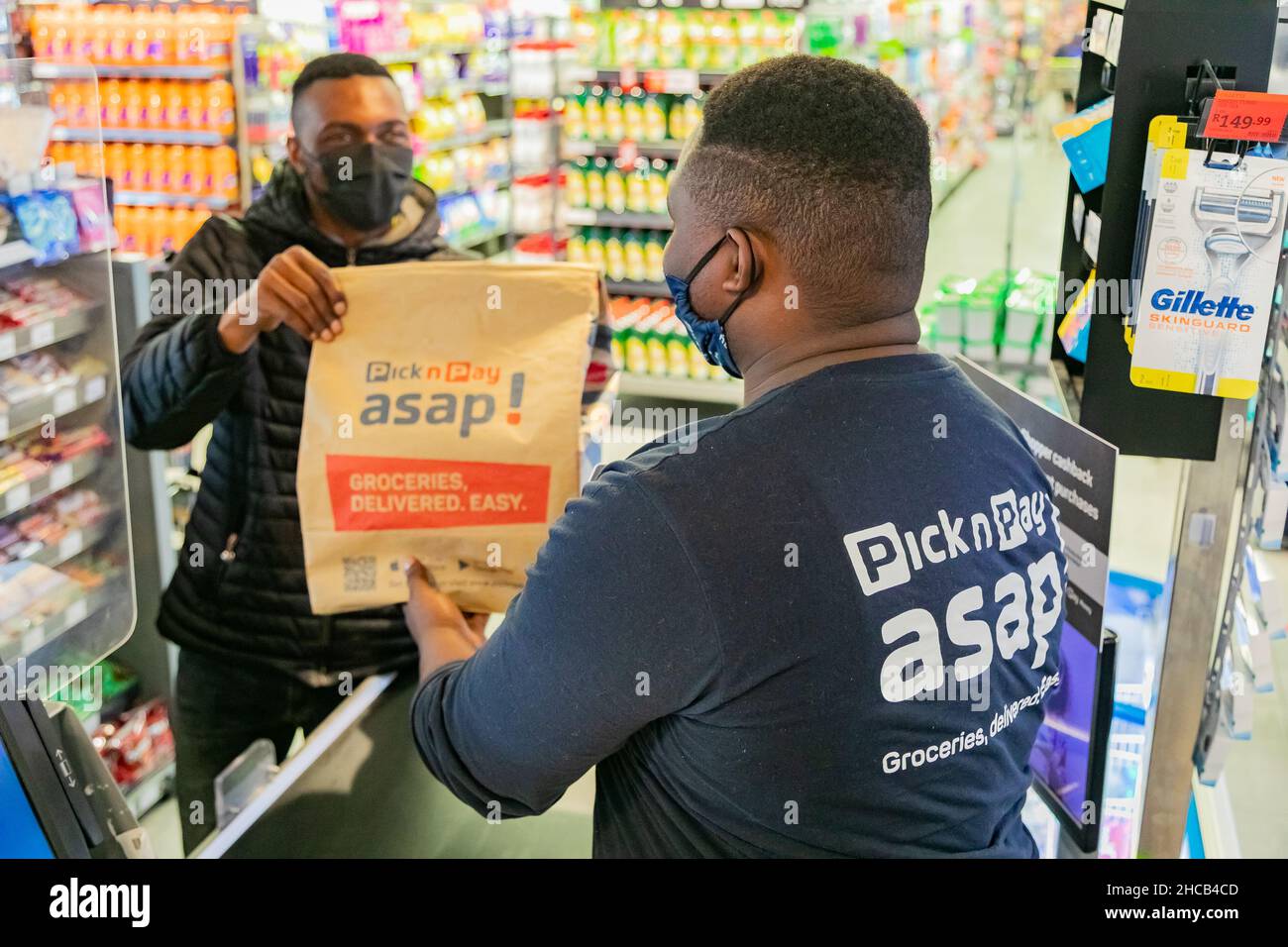 Cape Town, Afrique du Sud - 9 septembre 2021 : le livreur Express Service collecte la commande auprès du personnel au comptoir à l'intérieur de l'épicerie locale Pick n Pay Banque D'Images