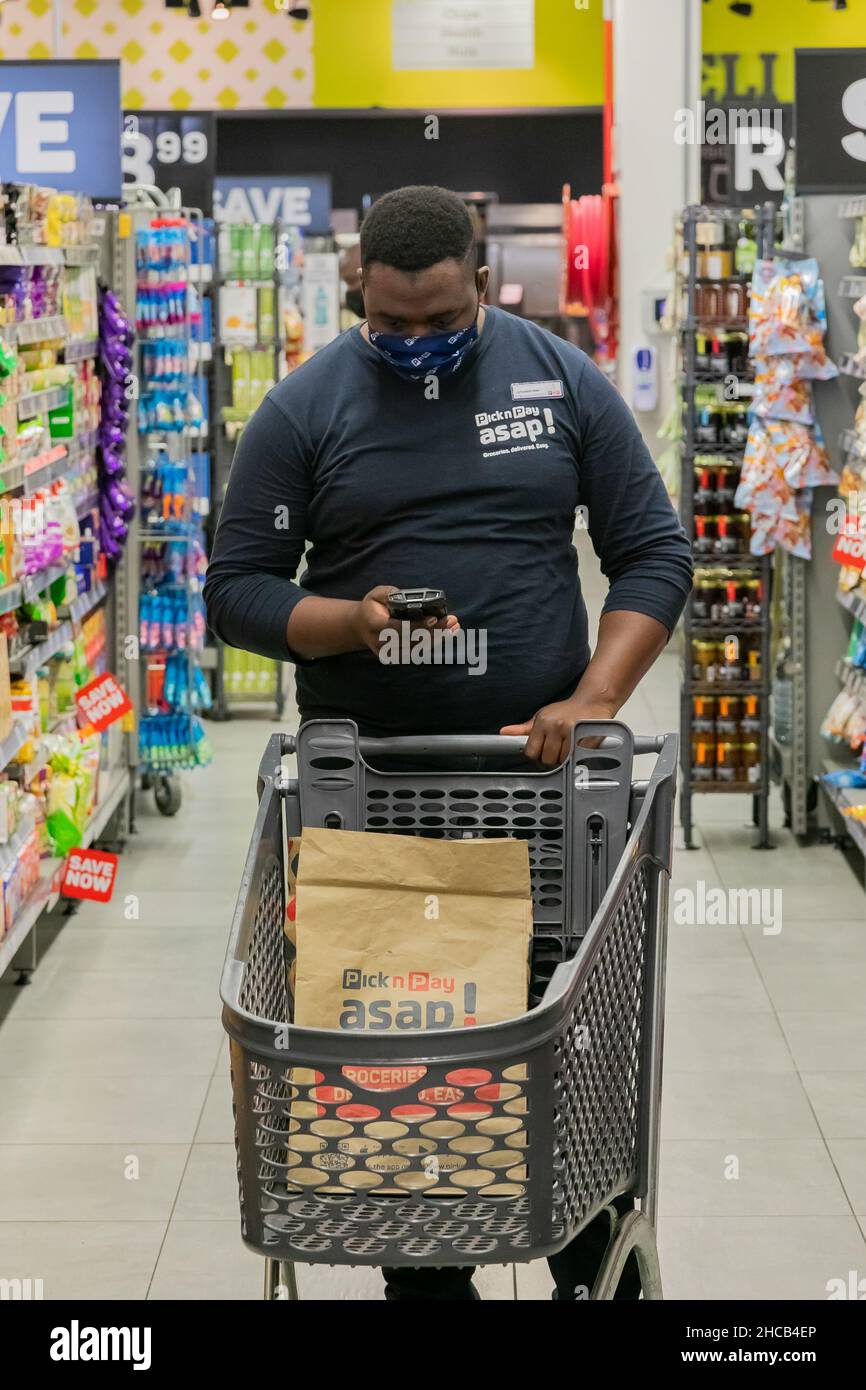 Cape Town, Afrique du Sud - 9 septembre 2021 : un membre du personnel cueille des produits à partir de l'étagère pour un service de livraison express à domicile Banque D'Images