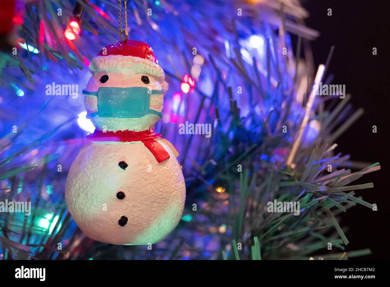 CARDIFF, PAYS DE GALLES - DÉCEMBRE 26: Sur cette photo, un bonhomme de neige décoré de Noël portant un masque chirurgical bleu est vu accroché à un arbre de Noël le 26 décembre 2021 à Cardiff, pays de Galles.Une version révisée des mesures d'alerte de niveau deux a été introduite le lendemain de Noël à 6am pour aider à atténuer la propagation de la variante du coronavirus Omicron. Banque D'Images